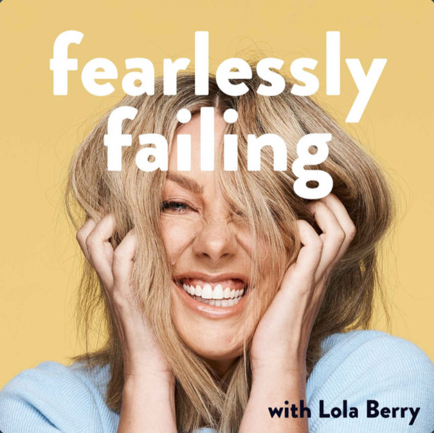 A woman with blonde hair and a big smile, holding her head with both hands, against a yellow background. Overlaid text reads 'fearlessly falling' and in smaller font 'with Lola Berry'.