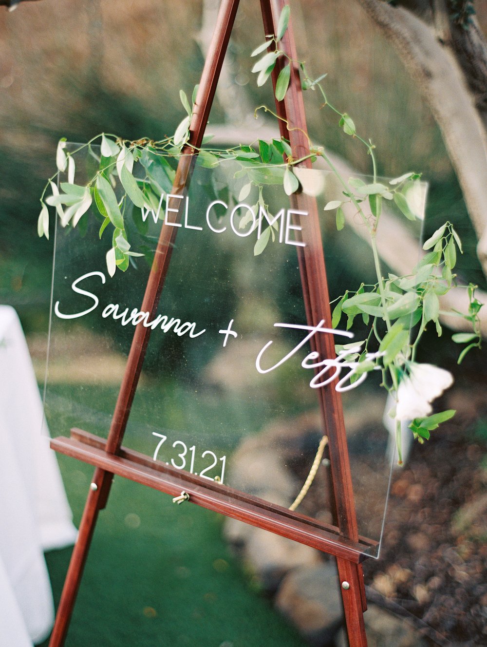Glass wedding welcome sign on a wooden easel.
