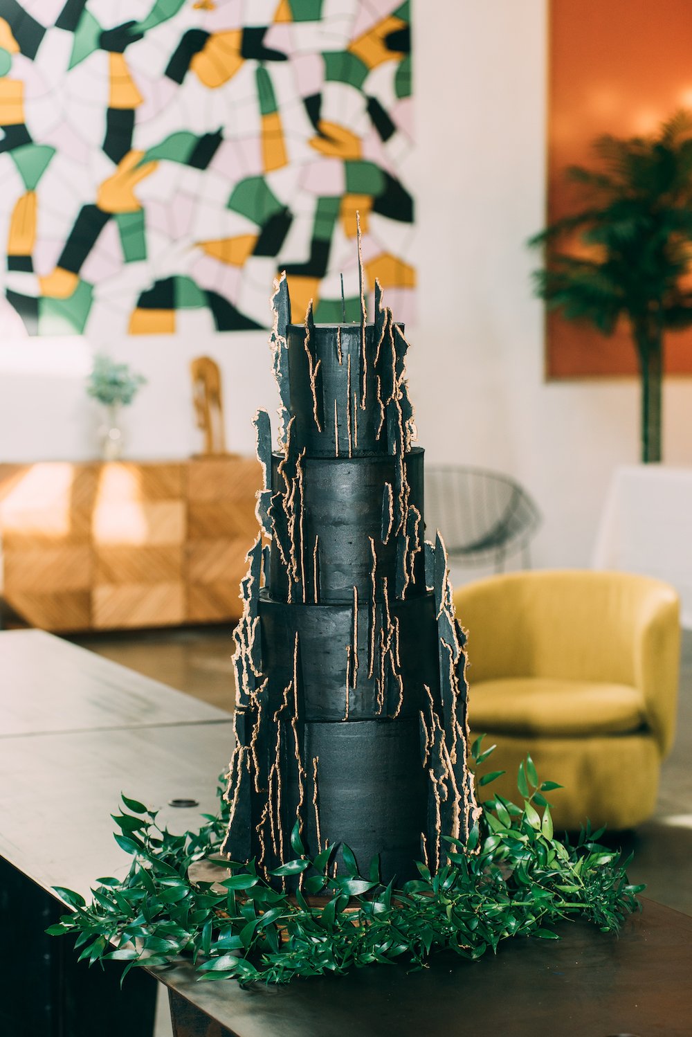 4-tier black eclectic wedding cake with gold details.