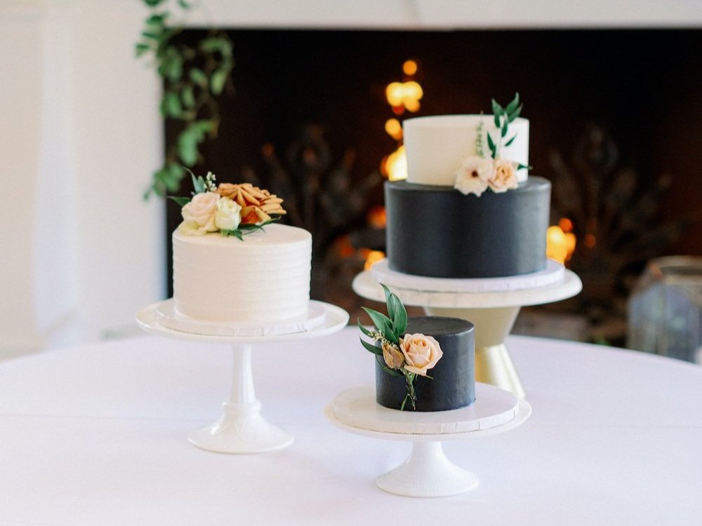 Multiple wedding cake display with 3 black and white cakes on cake stands. 