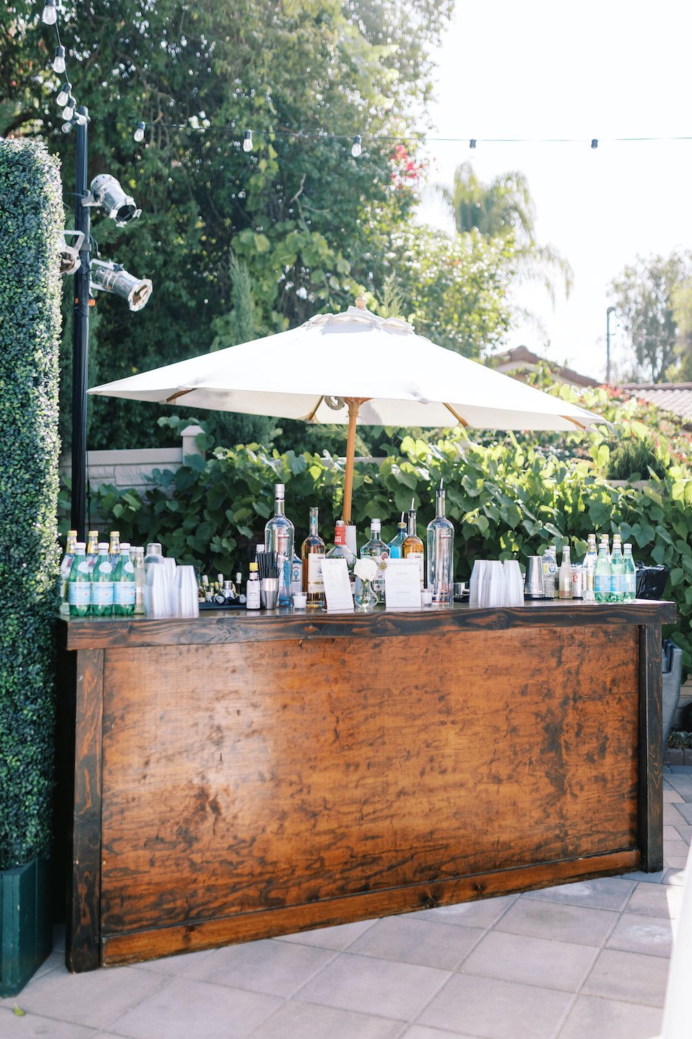 Backyard wedding bar station with an umbrella.