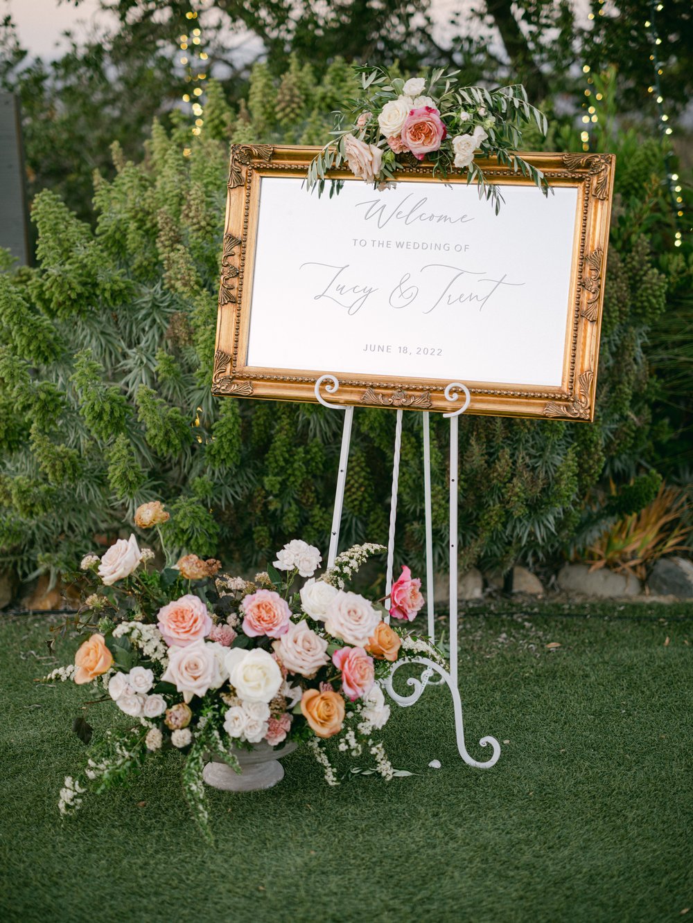 Wedding reception seating chart sign with pink and orange floral sprays.