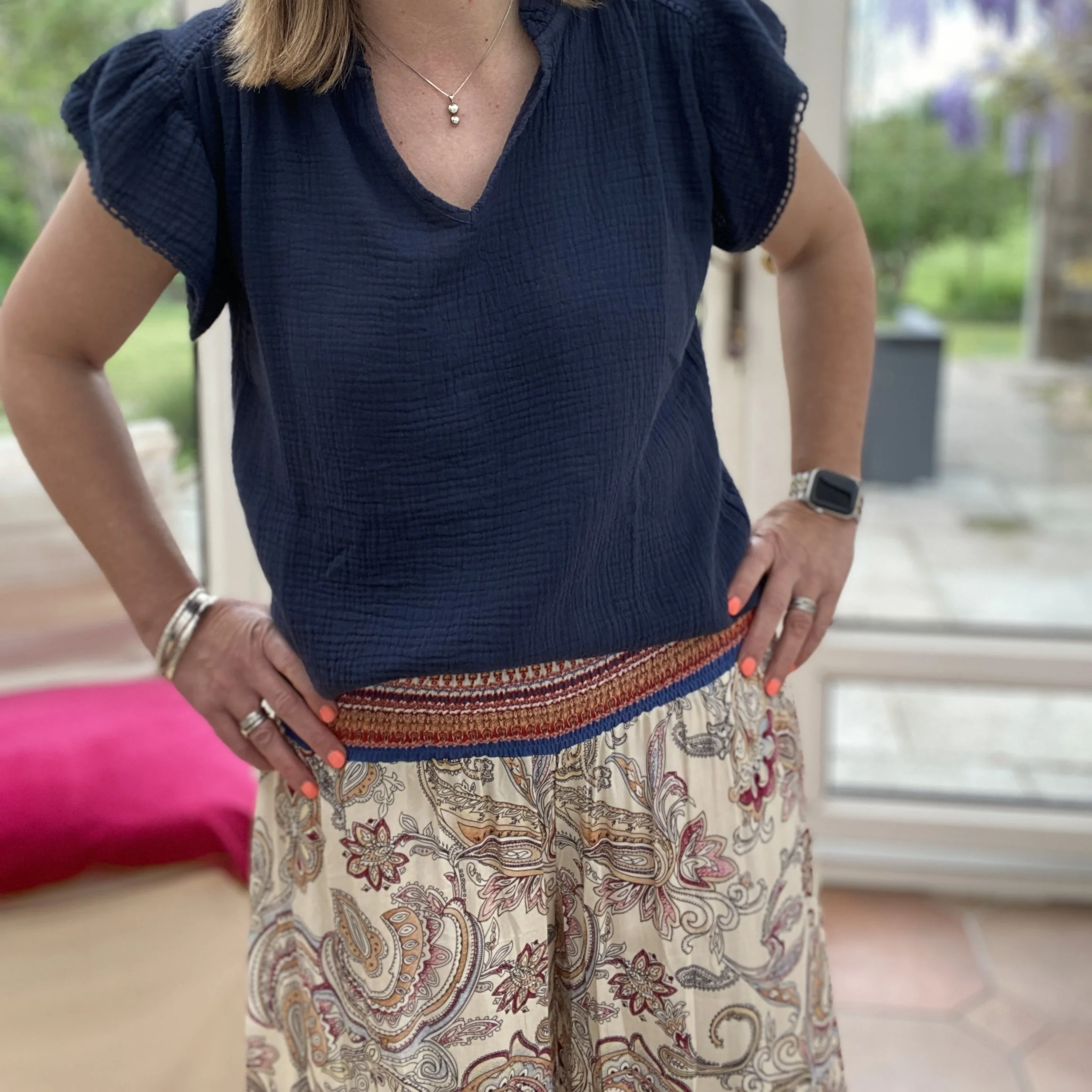 model wearing a navy blue short sleeve top with some paisley patterned wide leg trousers with an deep elasticated waistband