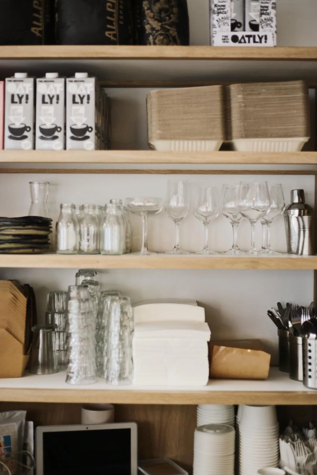 Shelves with coffee cups, glasses, and paper napkins in a café or restaurant.