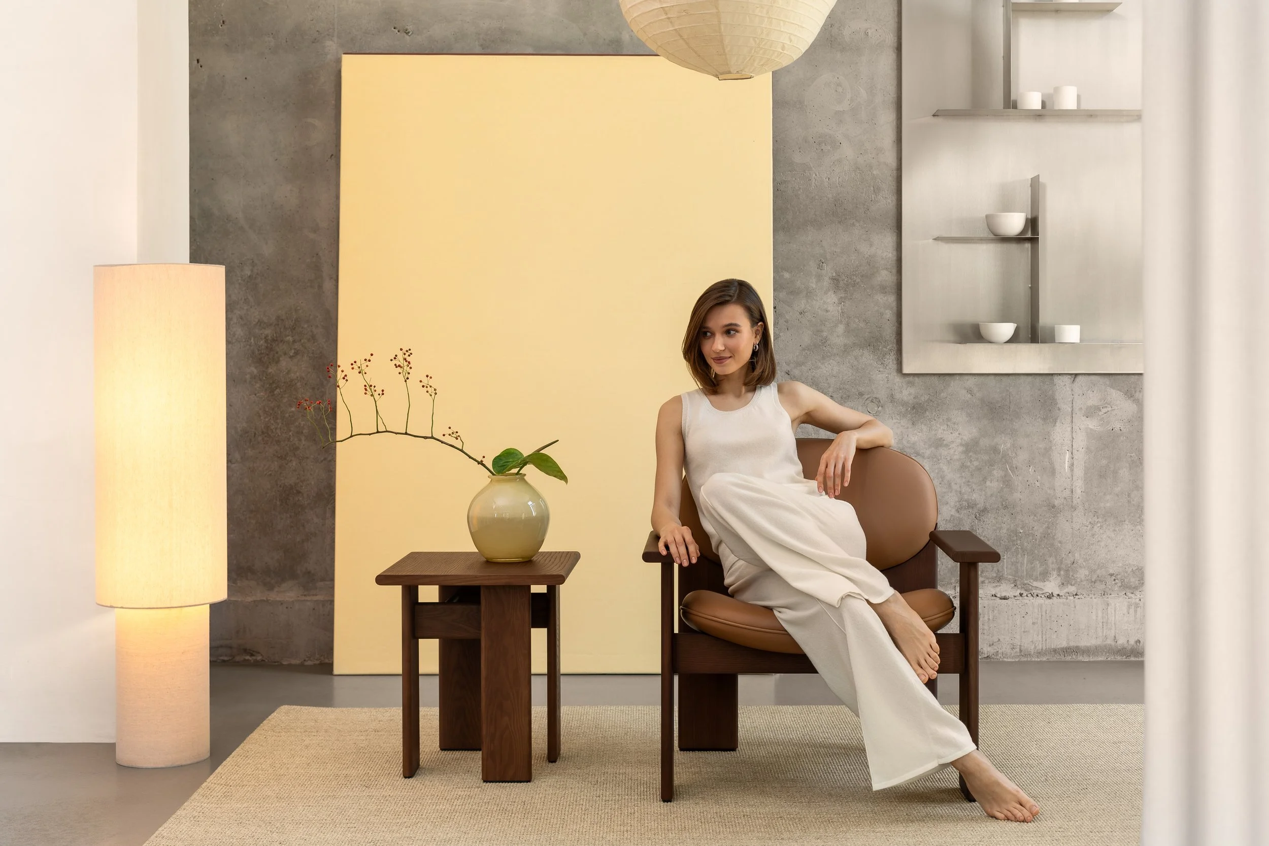 Modern lounge chairs with armrests and sculptural wooden bases. Fully customisable in colour, fabric, and finish.