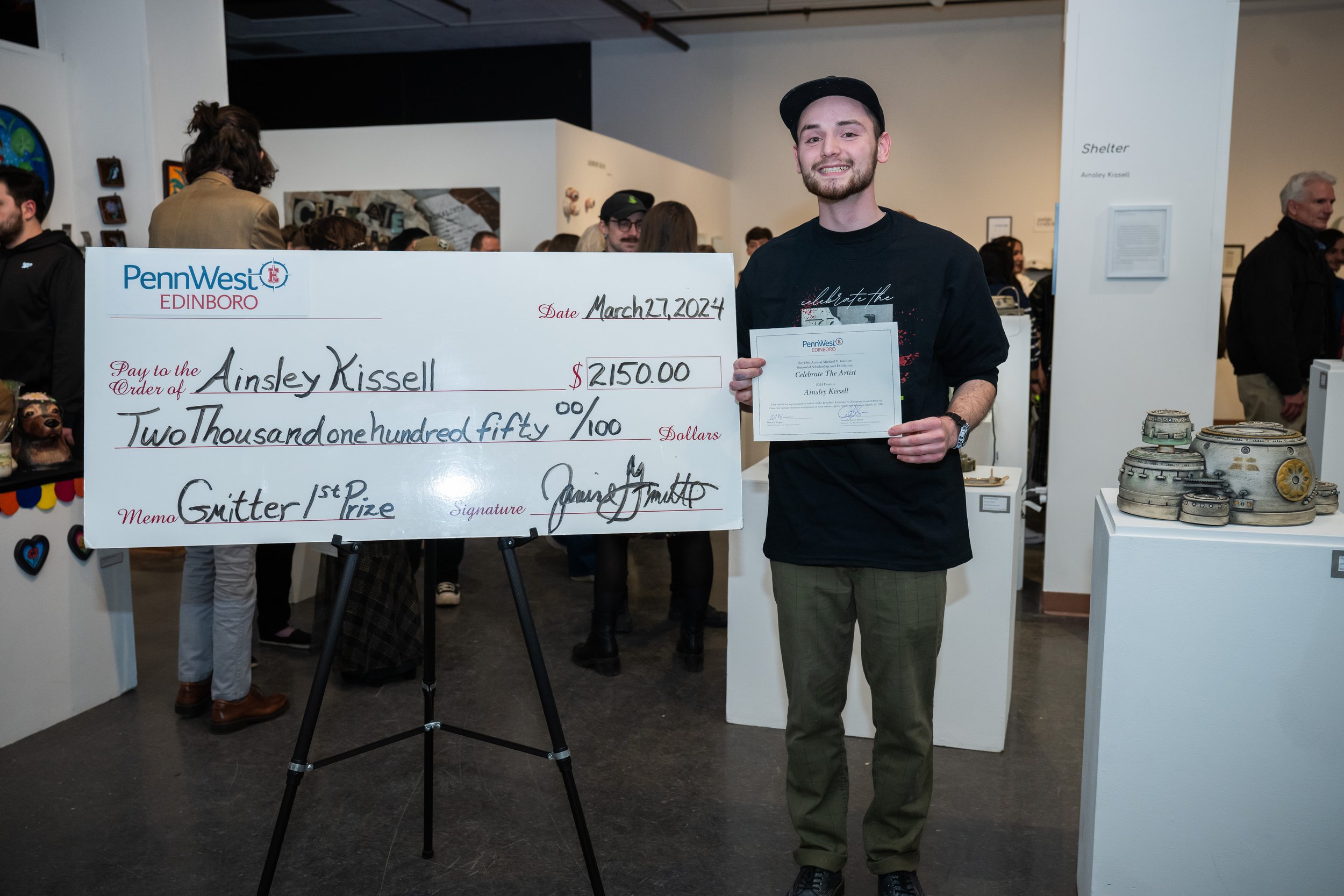EDINBORO, PA - Ainsley Kissel, Ceramics, in front of the first place check for the 15th annual Gmitter Scholorship Exhibition