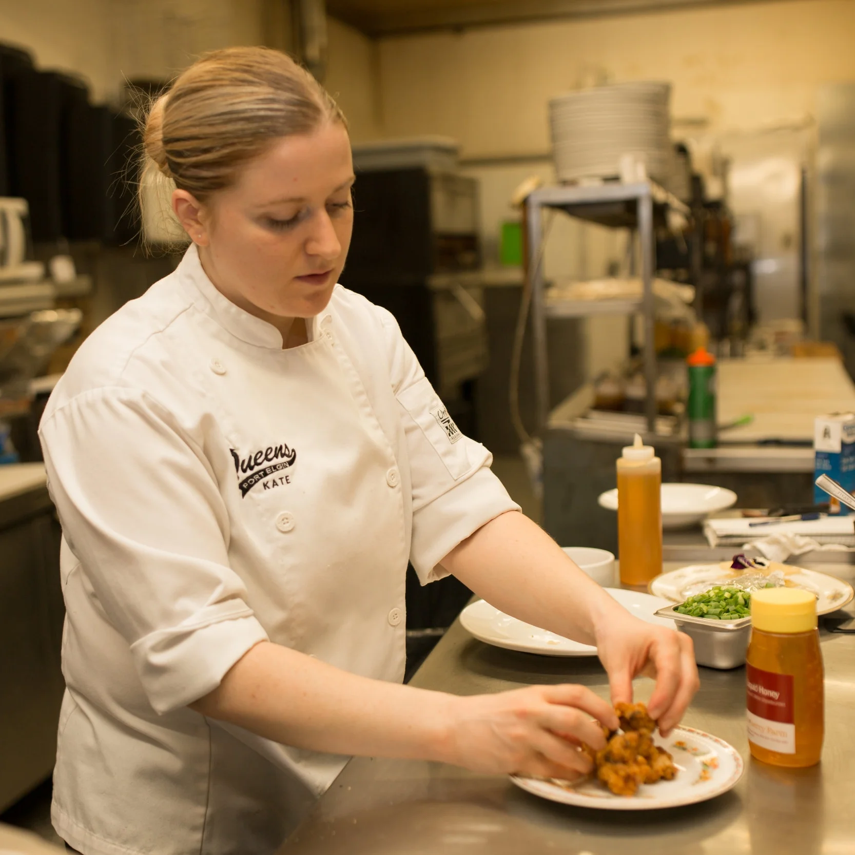 Kate Brewer of The Queens Bar and Grill prepares Corn & Green Onion Fritters with Bacon Honey