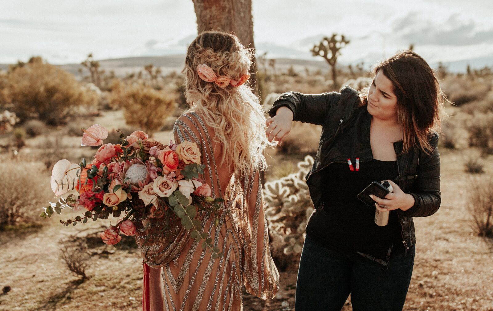 Outdoor photo shoot with engaged bohemian bride with hair stylist holding sustainable and organic peach flower bouquetOutdoor photo shoot with engaged bohemian bride with hair stylist holding sustainable and organic peach flower bouquet