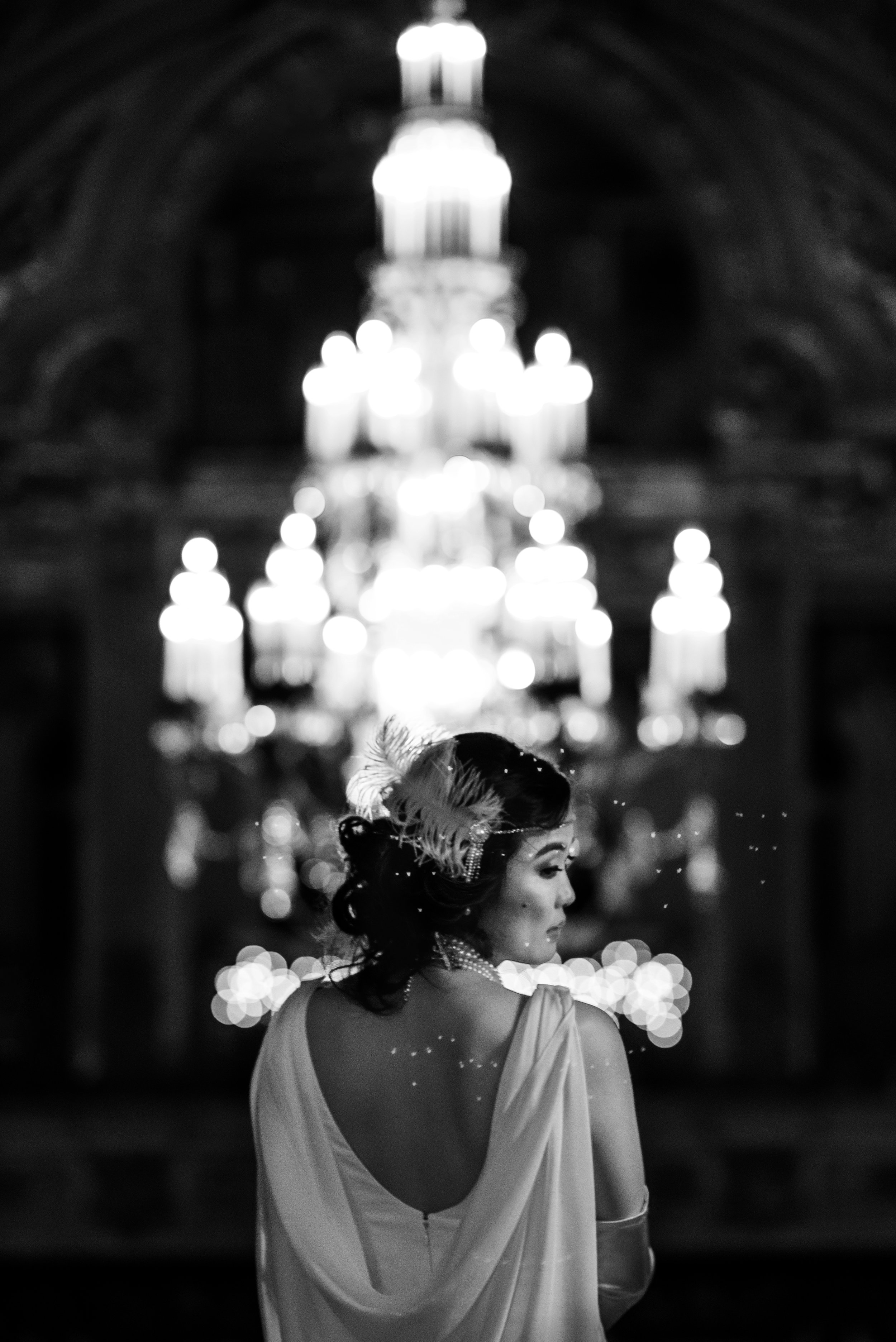 Stunning black and white portrait of bride's white backless gown and 20s inspired feather head piece and pearl necklace