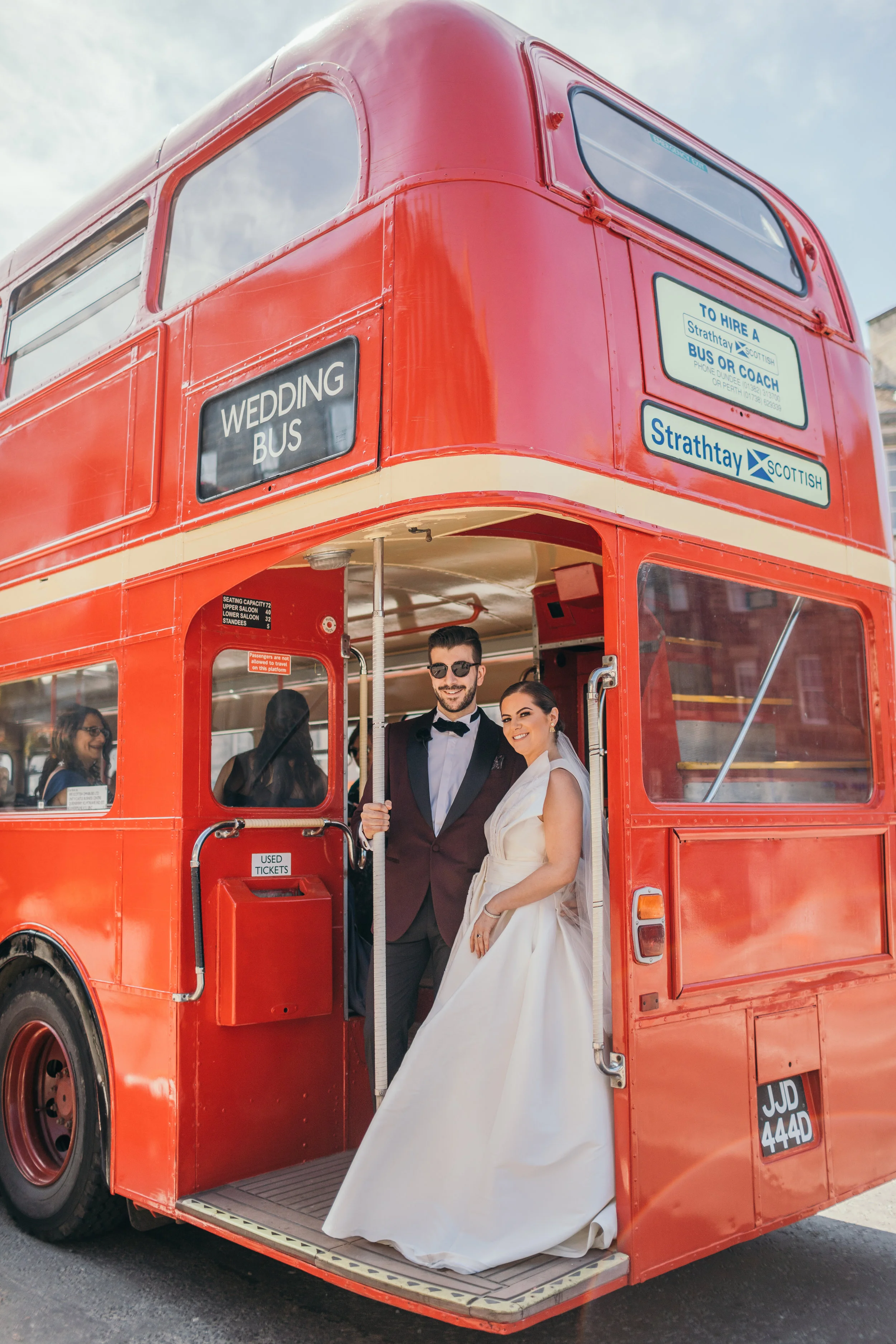 Portrait bride and groom in red double decker bus in Scotland Castle Outdoor Destination Wedding