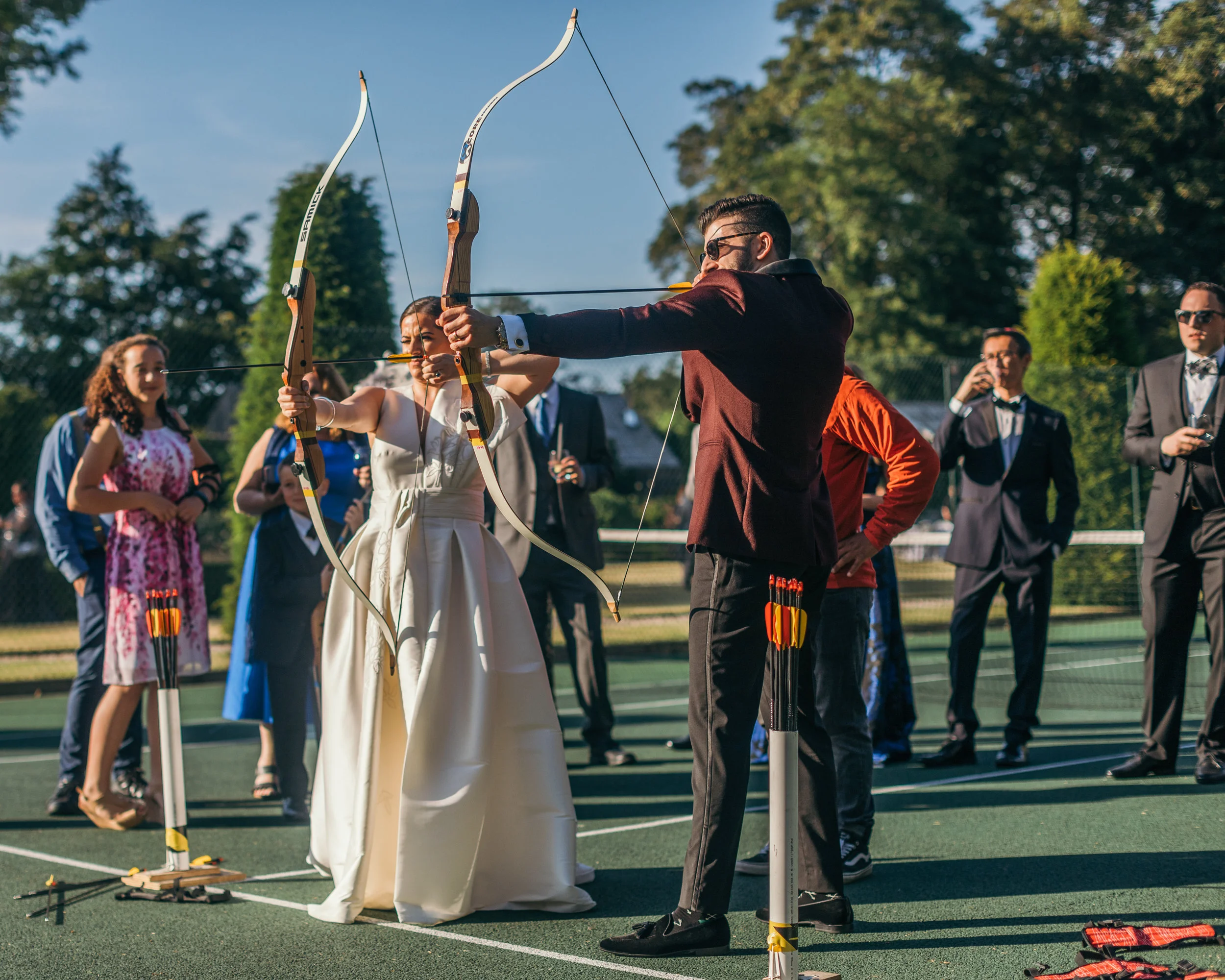 Bride and groom shooting bow and arrows in Scotland summer castle outdoor wedding