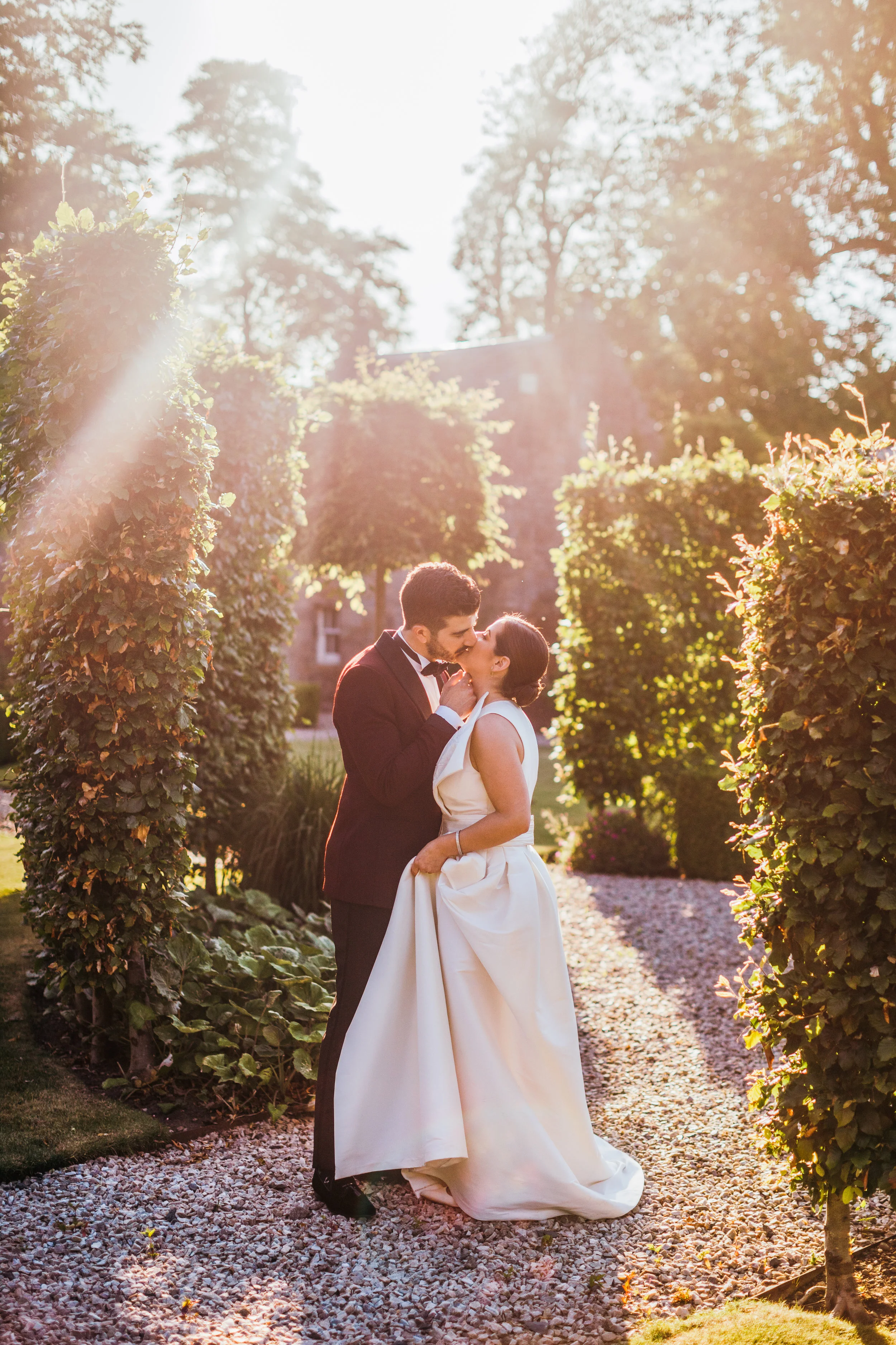 Beautiful portrait of bride and groom kissing outside the Scotland castle surrounded by greenery