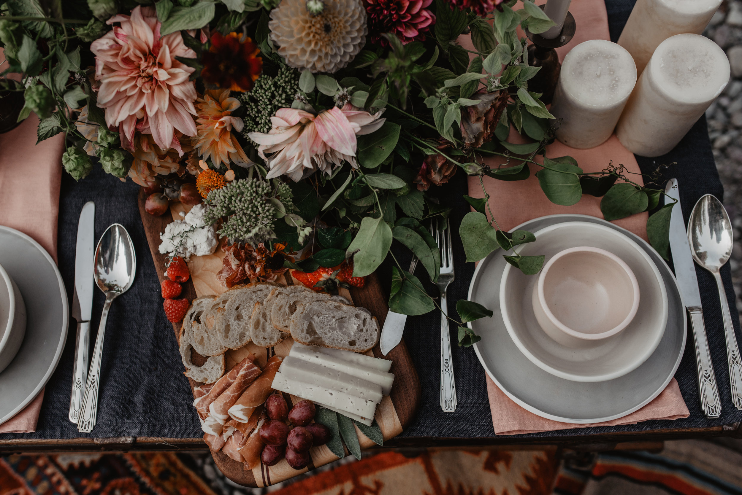 Beautiful table scape filled with locally sourced charcuterie, sustainable flower arrangements, plating and candles
