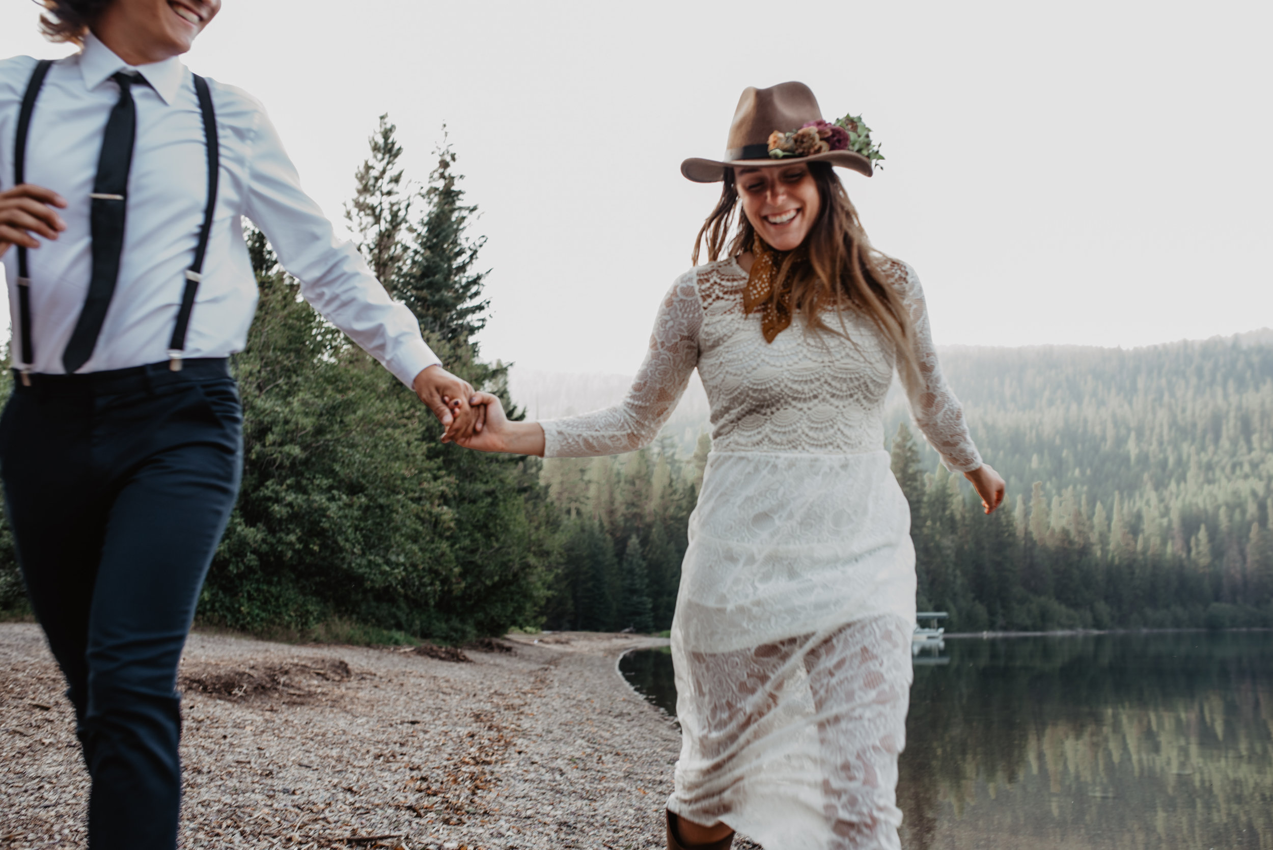 Outdoor sustainable elopement photo shoot of happy engaged couple holding hands at Glacier National Park MT