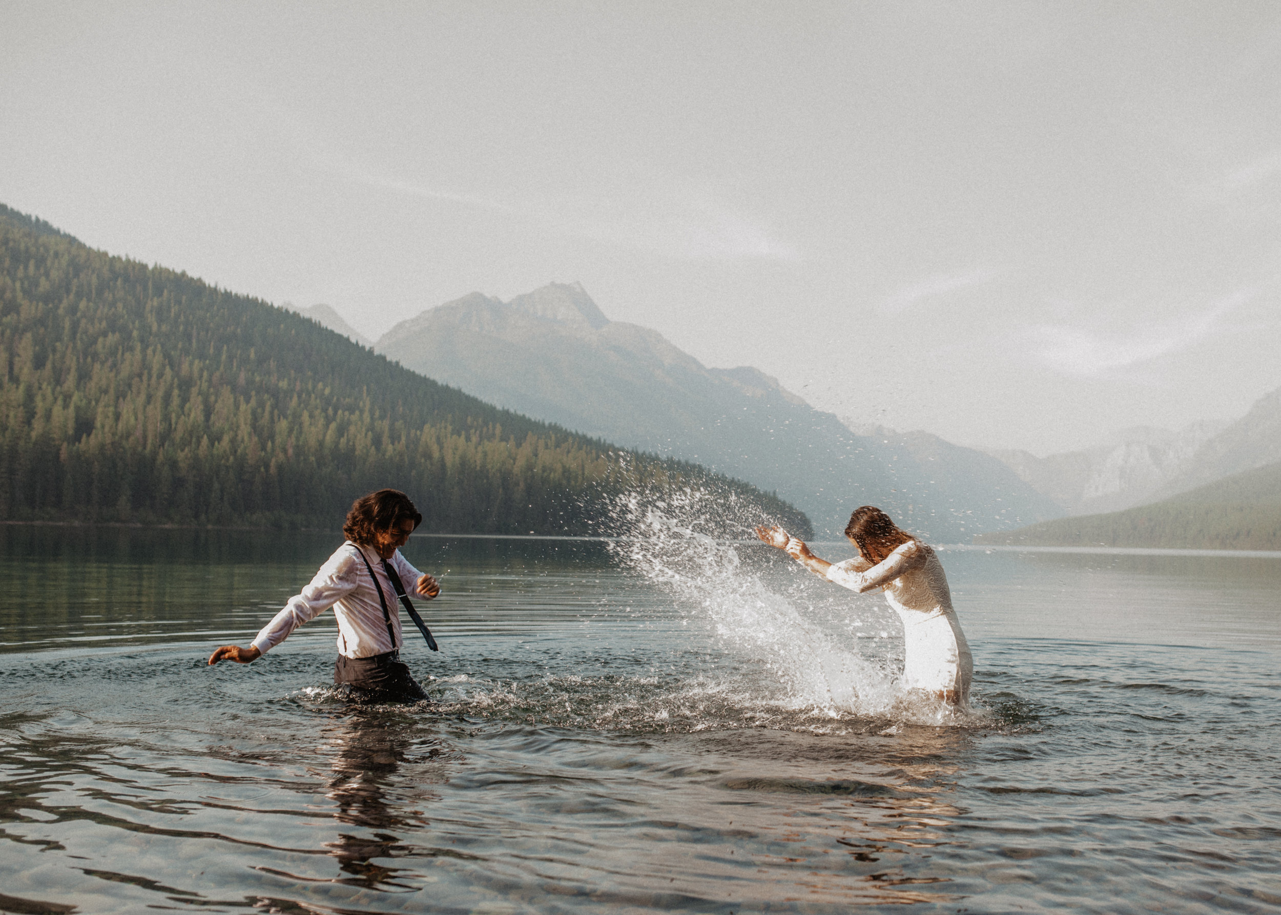 Outdoor elopement portrait of engaged couple splashing in water at Glacier National Park MT