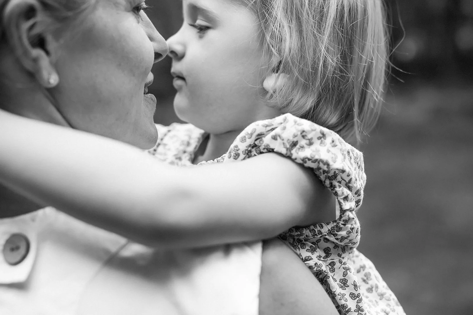 A young girl and an older woman are close together, touching noses, with the girl’s arms wrapped around the woman in an affectionate embrace.