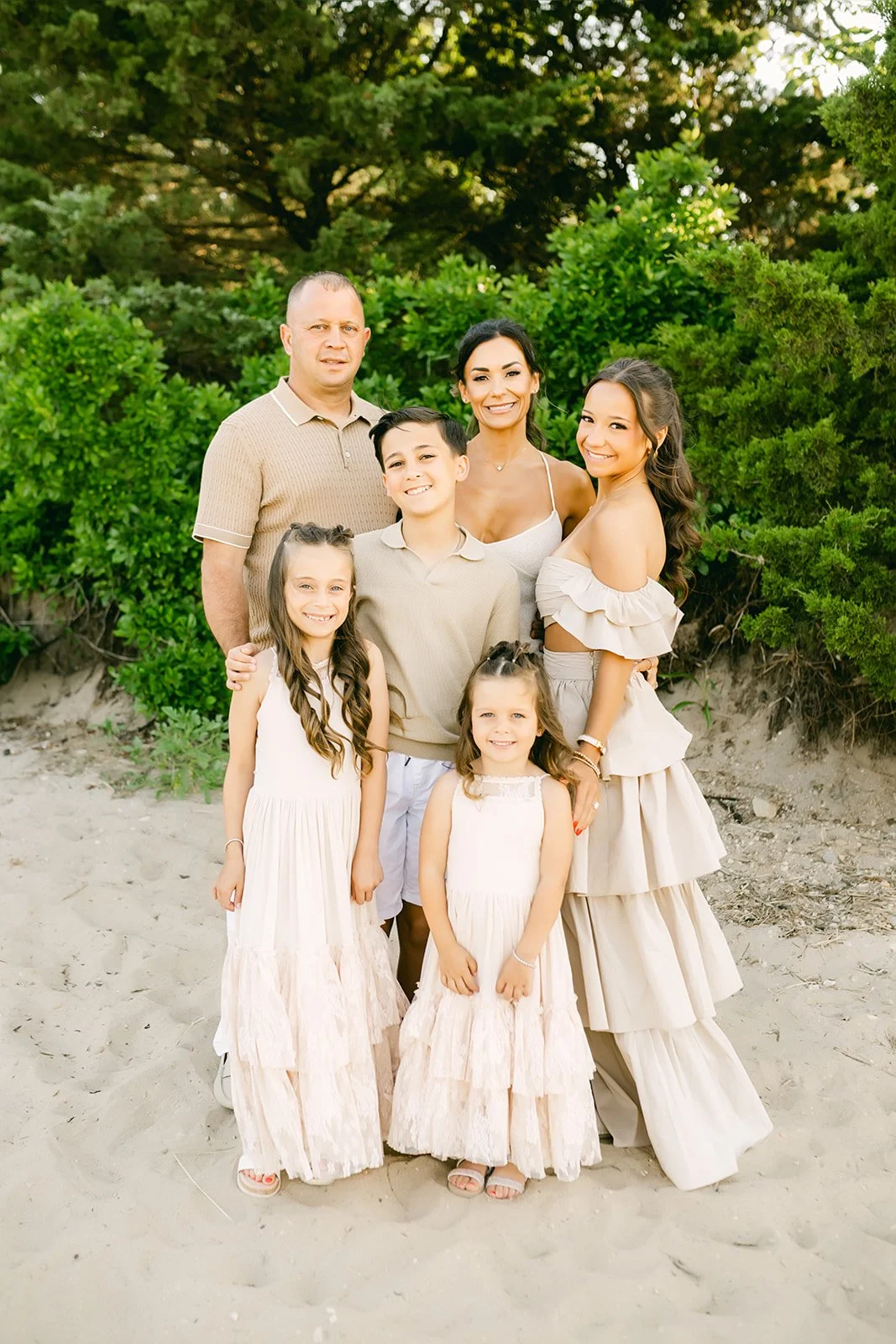 Family photos on the beach with four children and two women, surrounded by greenery.