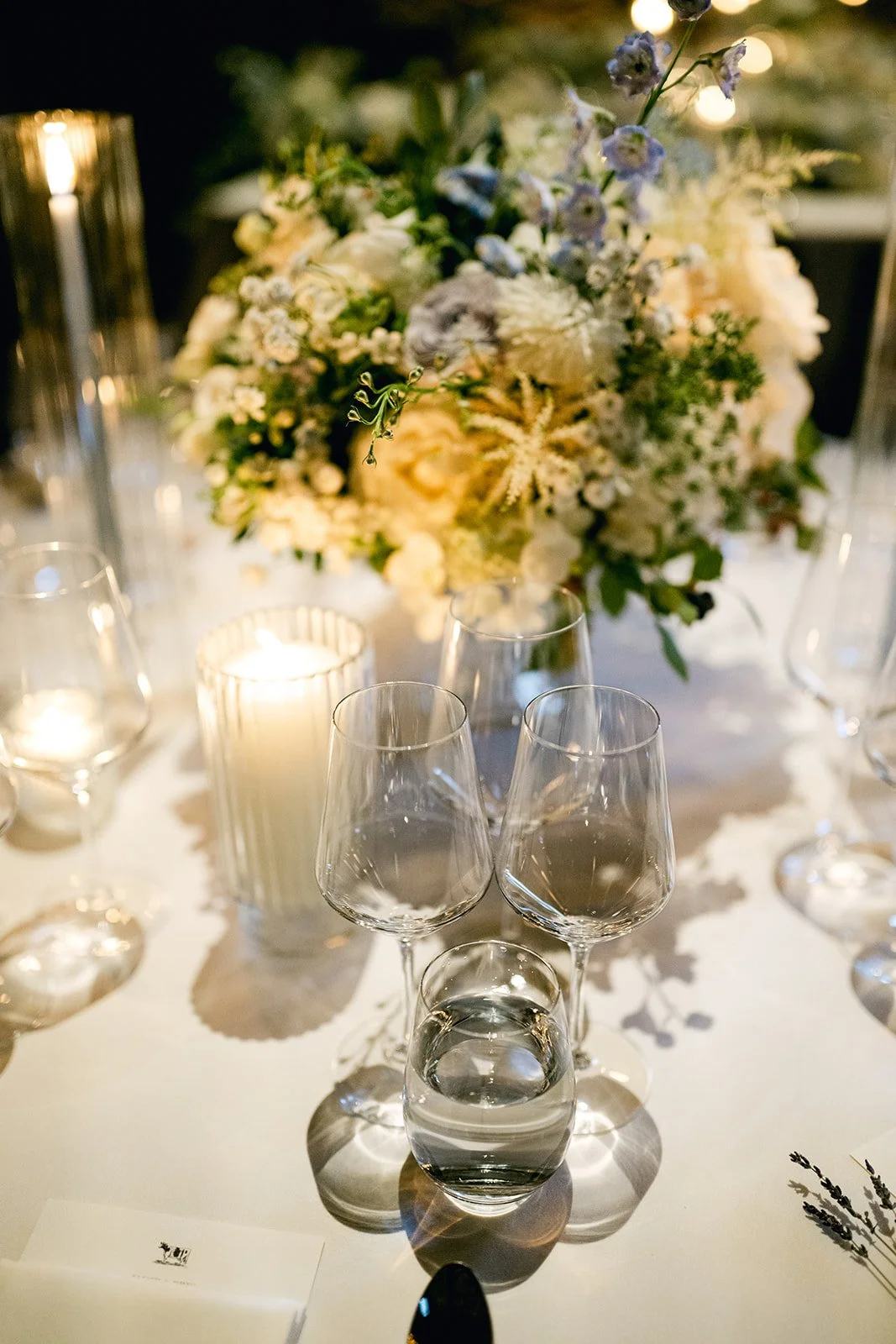 Elegant table setting with a floral centerpiece, candles, and wine glasses.