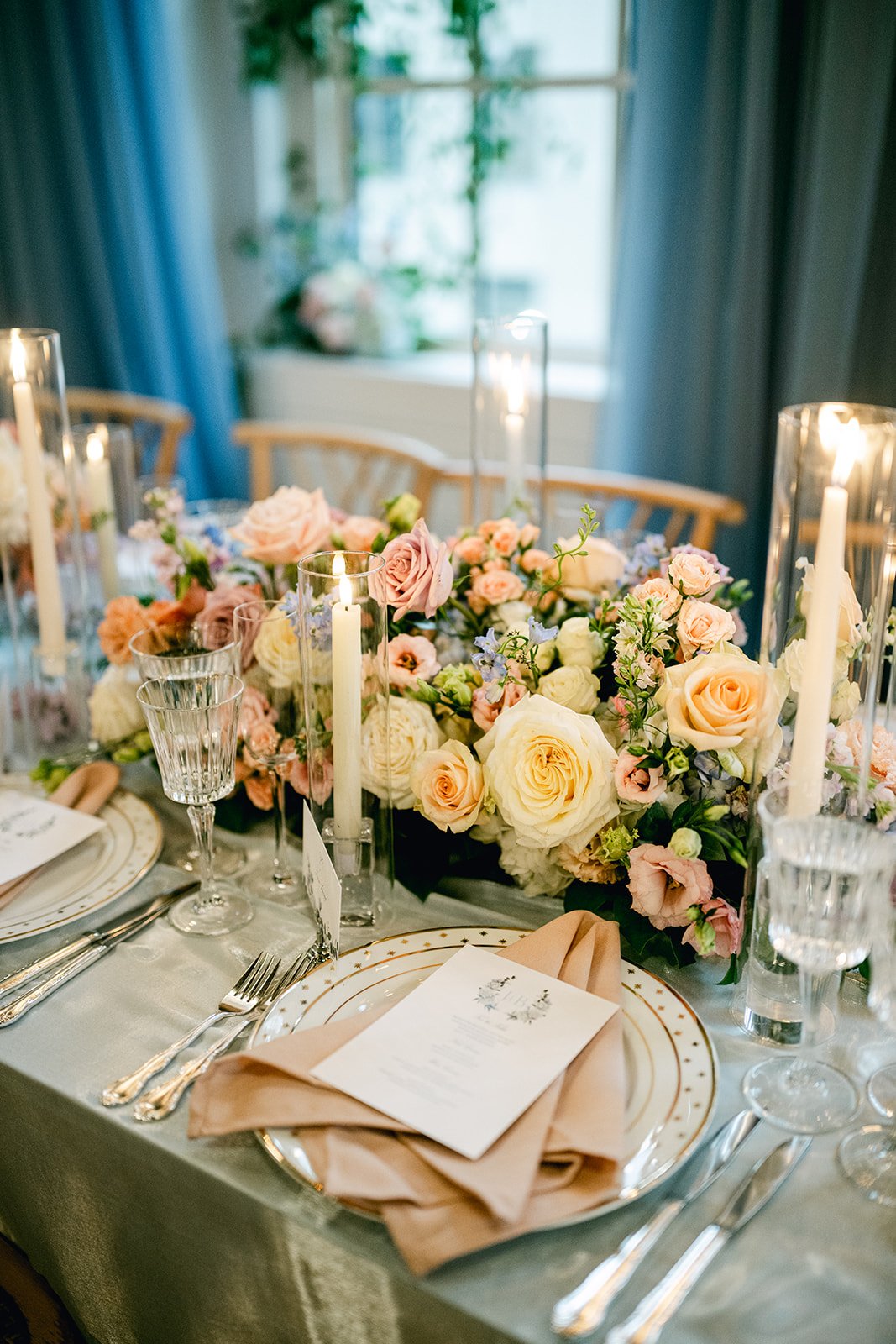 Elegant dining table set with pink and white flowers, candles, fine china, and glassware for a special occasion.