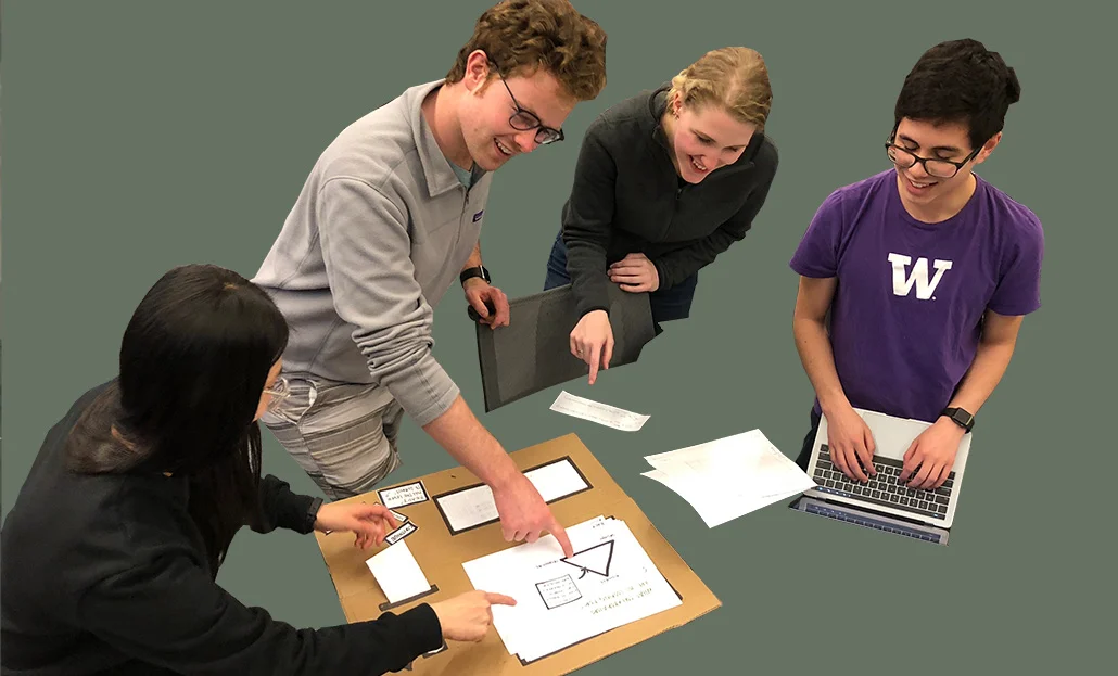 Classmates discuss an early prototype while Harrison (right) takes notes.