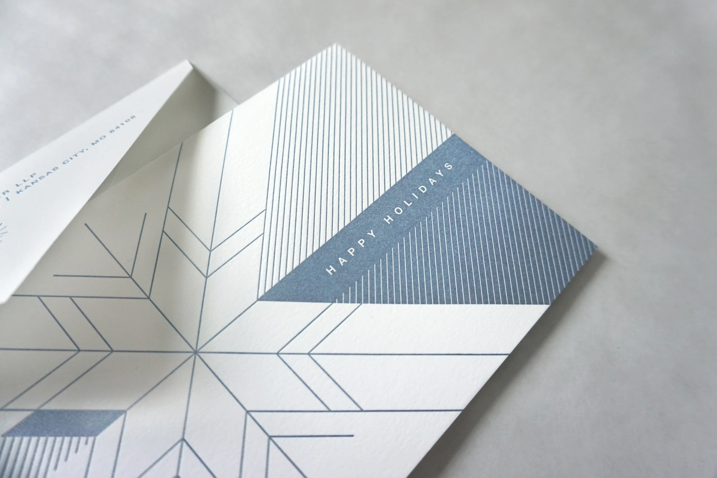 The card is letterpressed in metallic blue on the outside, and opens to reveal their primary brand color on the inside.