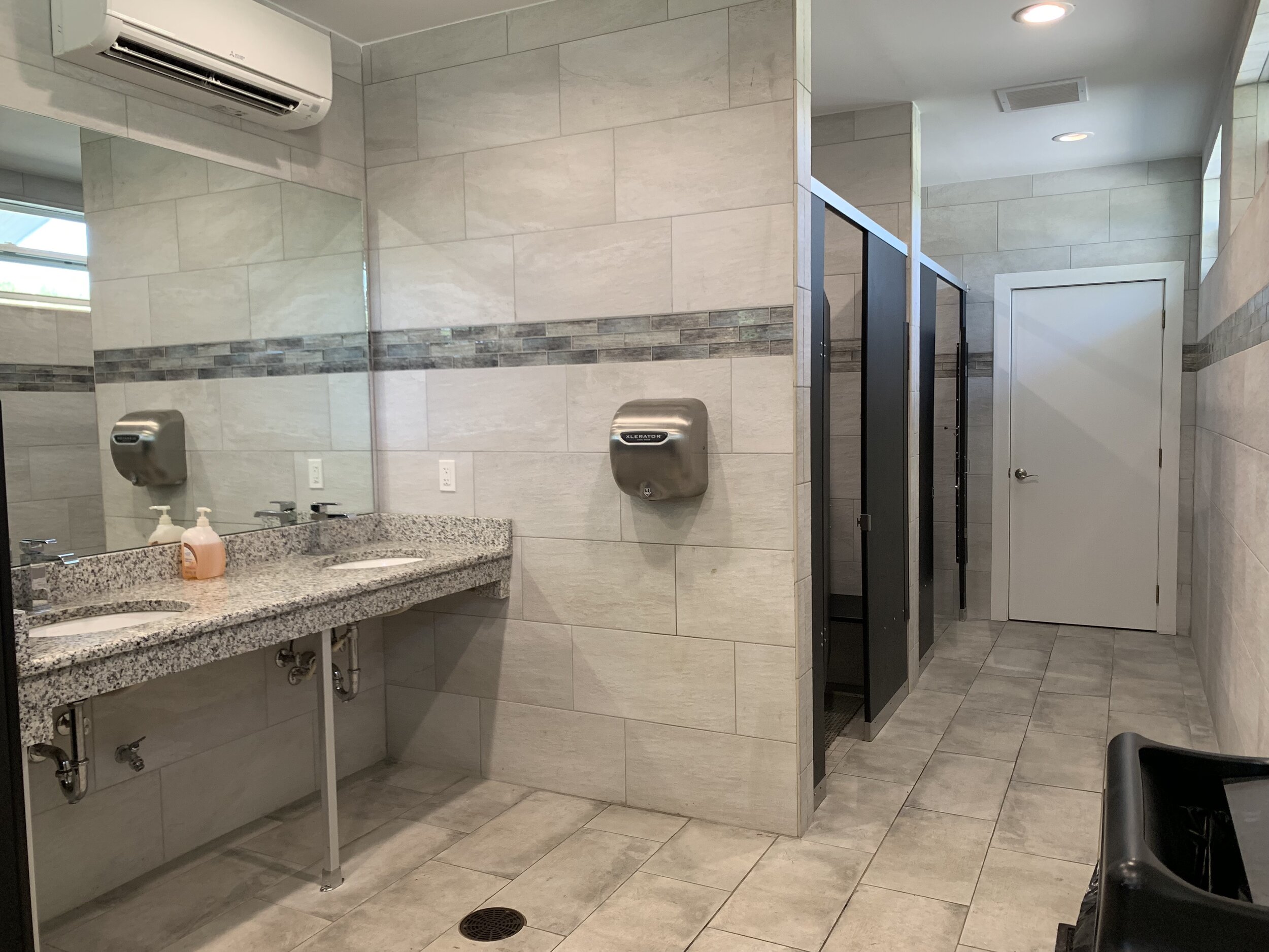Restroom with two sinks, soap dispensers, hand dryer, lockers, and a closed door.