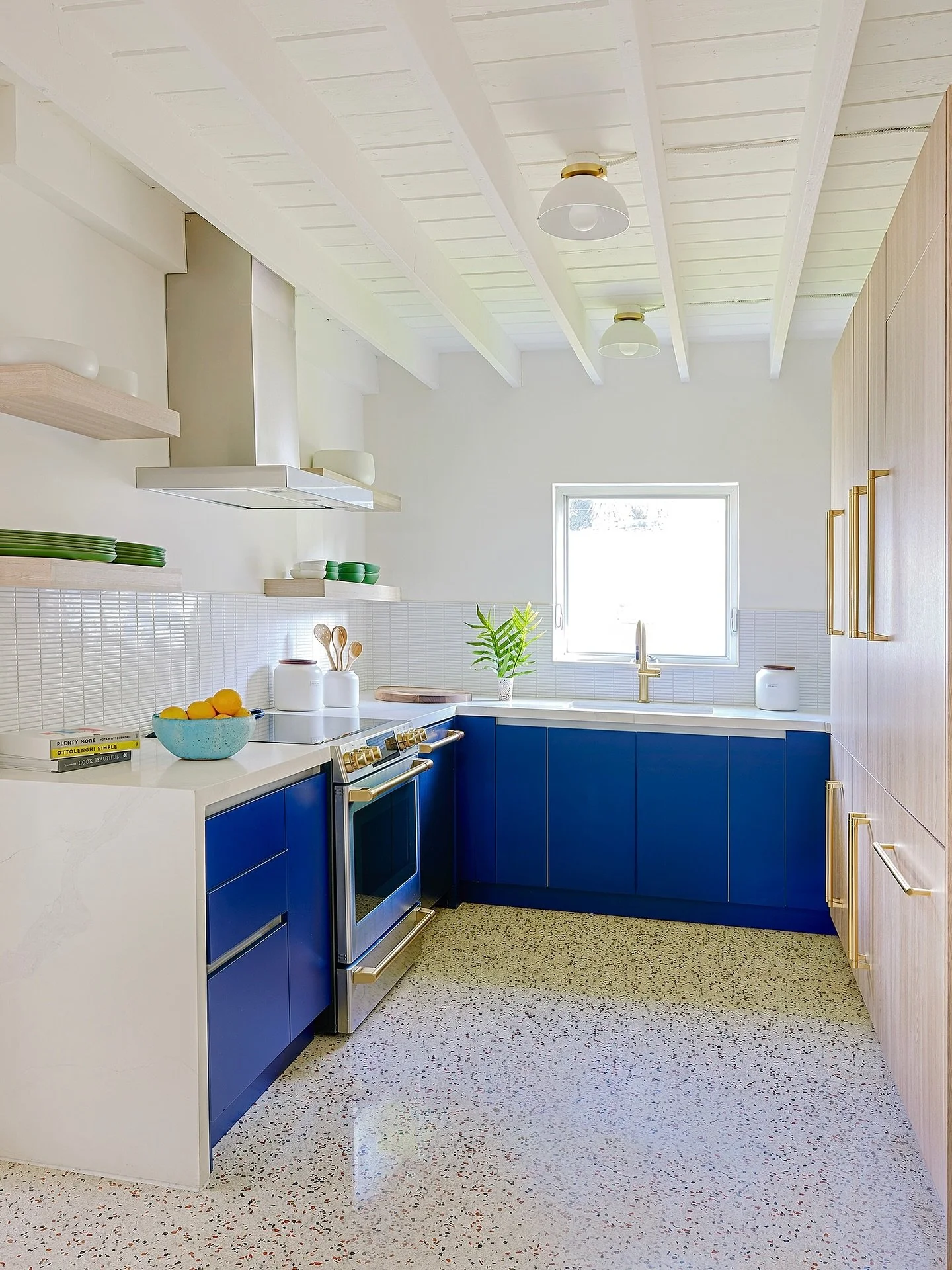 Crisp white walls and terrazzo floors keep the mood airy in this Florida bungalow.&nbsp; Cobalt blue cabinetry and brass accents add the fun. A mix of open shelving and streamlined cabinets&nbsp;elevate this coastal modern kitchen

Project: &ldquo;Ol