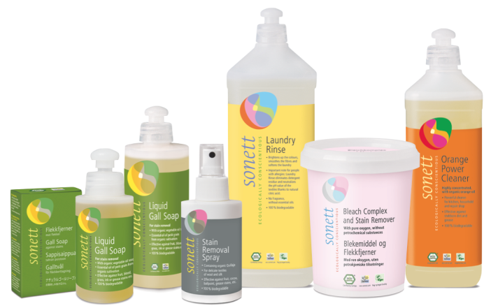 Sonett eco-friendly laundry and cleaning products, including liquid gall soap, stain removal spray, laundry rinse, orange power cleaner, and bleach complex with stain remover, in bottles and boxes with bright colored labels. Stain removal tips.
