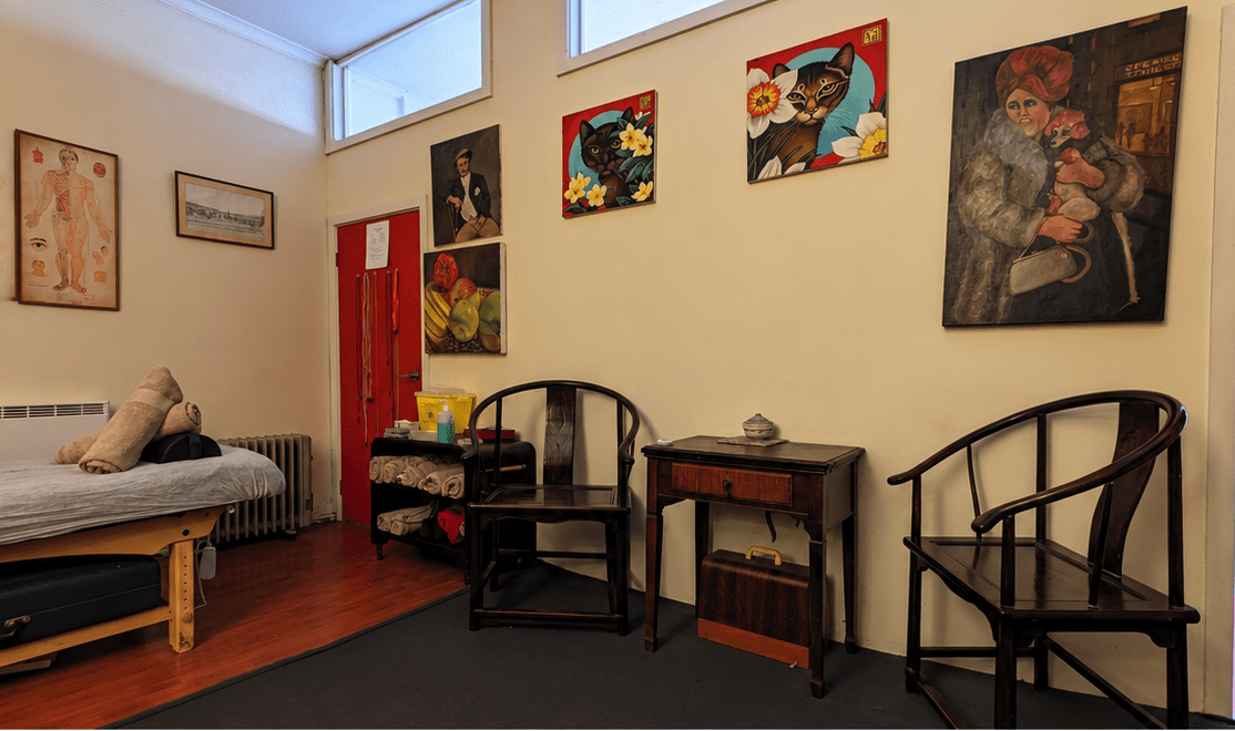 depicting consultation space of wooden chairs  with the acupuncture treatment bed adjacent