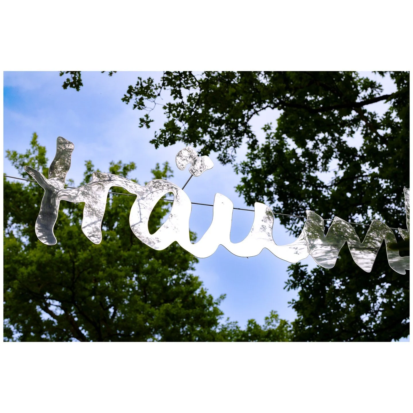 als wir tr&auml;umten &copy; Ursula Palla

Der Schriftzug &quot;als wir tr&auml;umten&quot; schwebt zwischen den B&auml;umen im Park und bewegt sich leicht im Wind. Die Installation widerspiegelt die Umgebung fragmentiert und je nach Position sind in