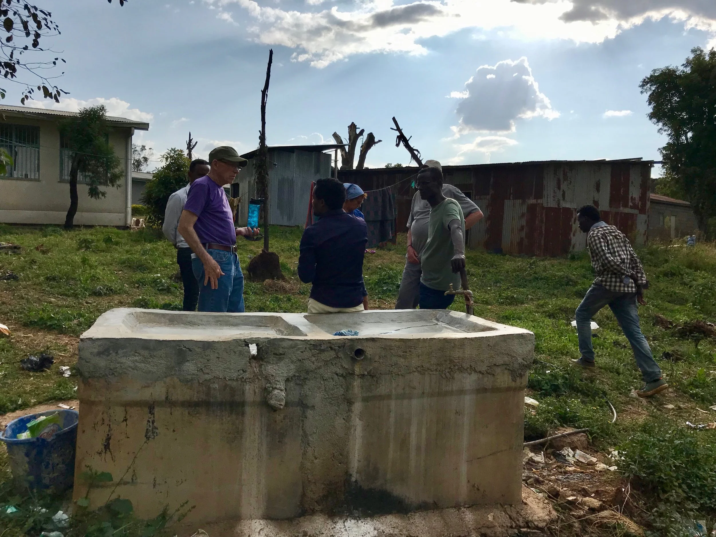 Daniel talks to Don about the need for a washer and dryer. Daniel is leaning on the laundry station where all the clinic laundry is done by hand.