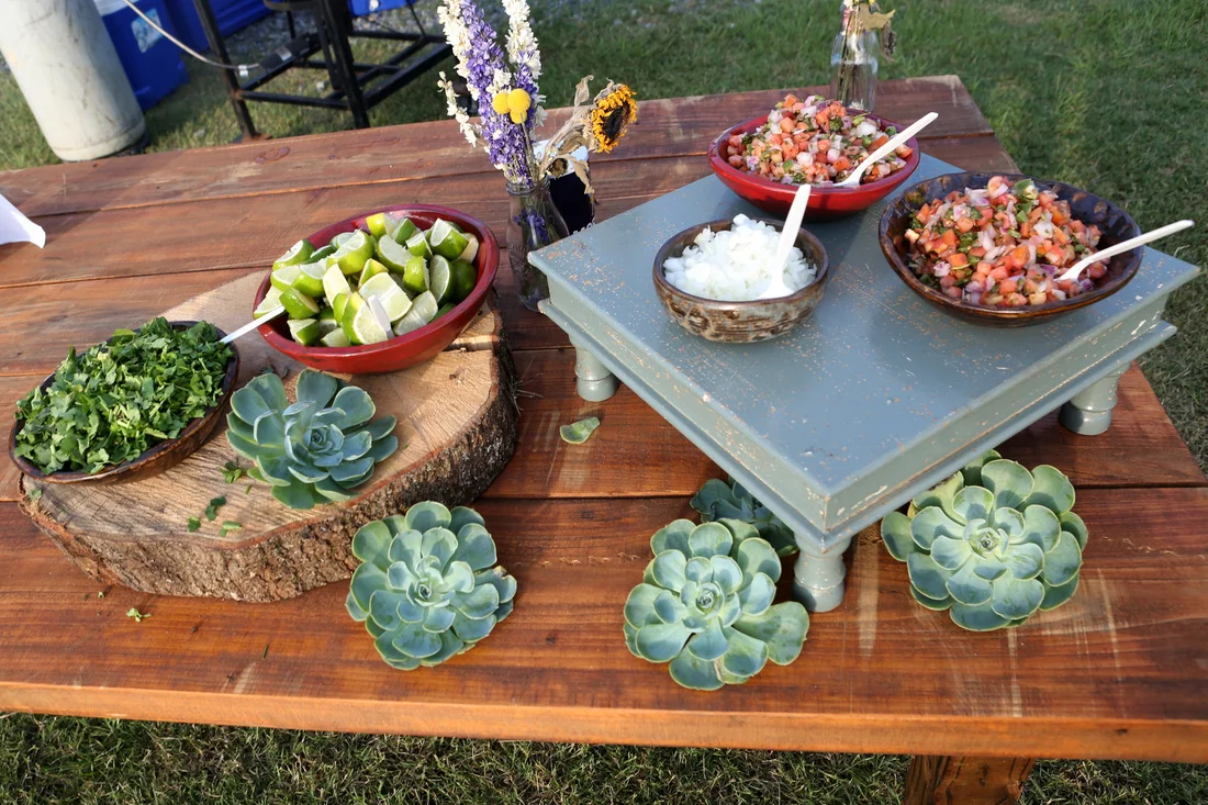We had to find JUST the right people to fix the reception food. Mary Kate wanted "bite sized" portions (similar to a food truck feel) and we found the right fit in Waterfront Grill . Their team prepared BBQ Shrimp and Brisket Sliders, Teriyaki Chicken Skewers with Vegetables and a Remoulade Salad. Our OAK catering team prepared Mini Chicken and Steak Tacos on a specialty "grill skillet" handmade for the event and roasted corn and peppers. The food was fantastic and everyone left with a full stomach! The reception décor was provided by OAK and through Ben Johnson's rentals. The farmhouse tables used as guest tables were handmade for this occasion for OAK (and we will be using them for years to come). With the help of some very generous OAK employees, I constructed, painted and distressed around 100 wooden candlesticks in 3 different colors and we used battery operated candles to give a great "glow" to the outdoors. Along with the entrees, guests had some fun options of Sno Cones (provided by John Luke and Willie's Ice Cabin ) and gourmet popcorn, provided by Farming for Humanity .
