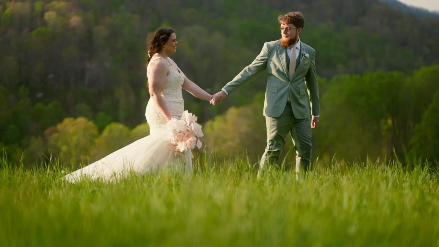 A couple walking hand in hand through a mountain meadow