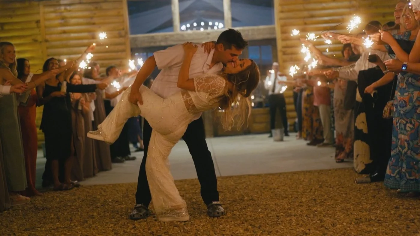 A groom dipping his bride for a kiss during a sparkler send-off