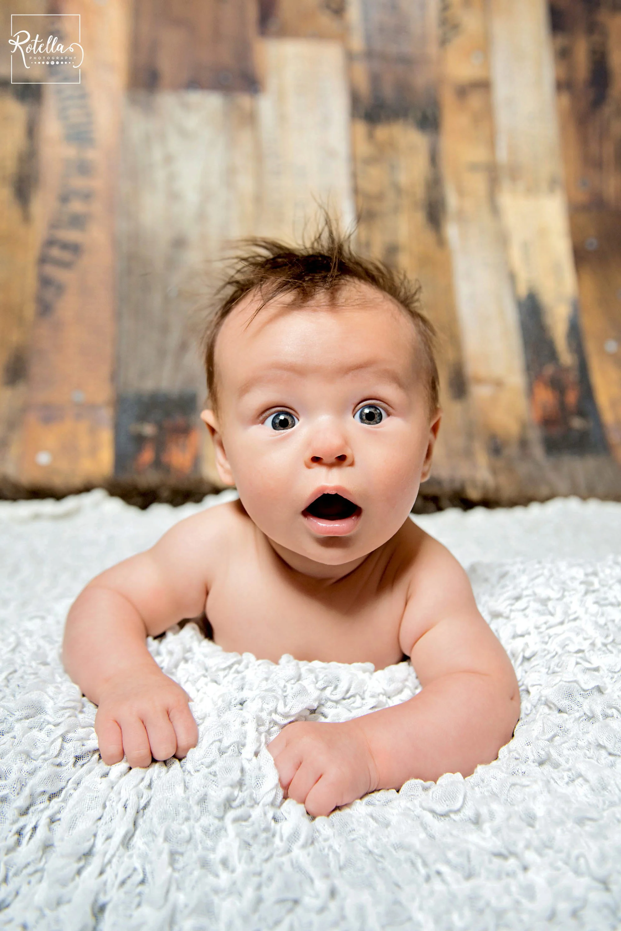 Rotella Photography - Baby on tummy on white blanket in photo studio