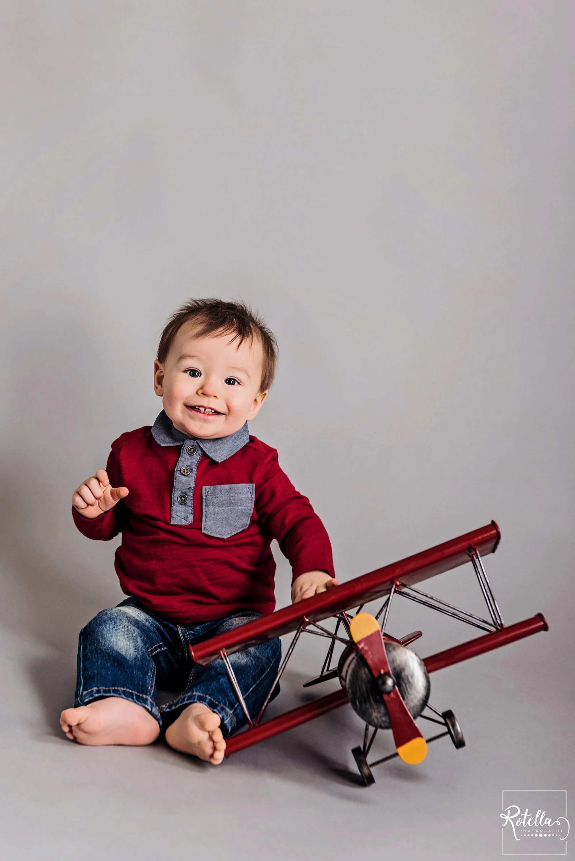 Rotella Photography - baby playing with red plane on grey backdrop