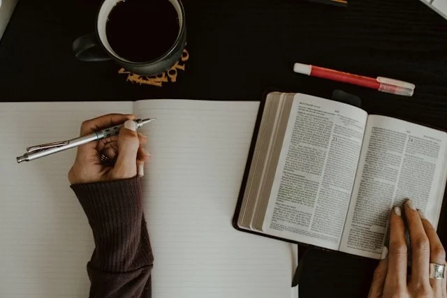 Woman with her Bible open ready to take notes in a journal