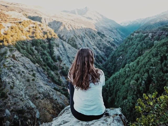 Woman sitting in the mountains wondering if Christians should follow their dreams