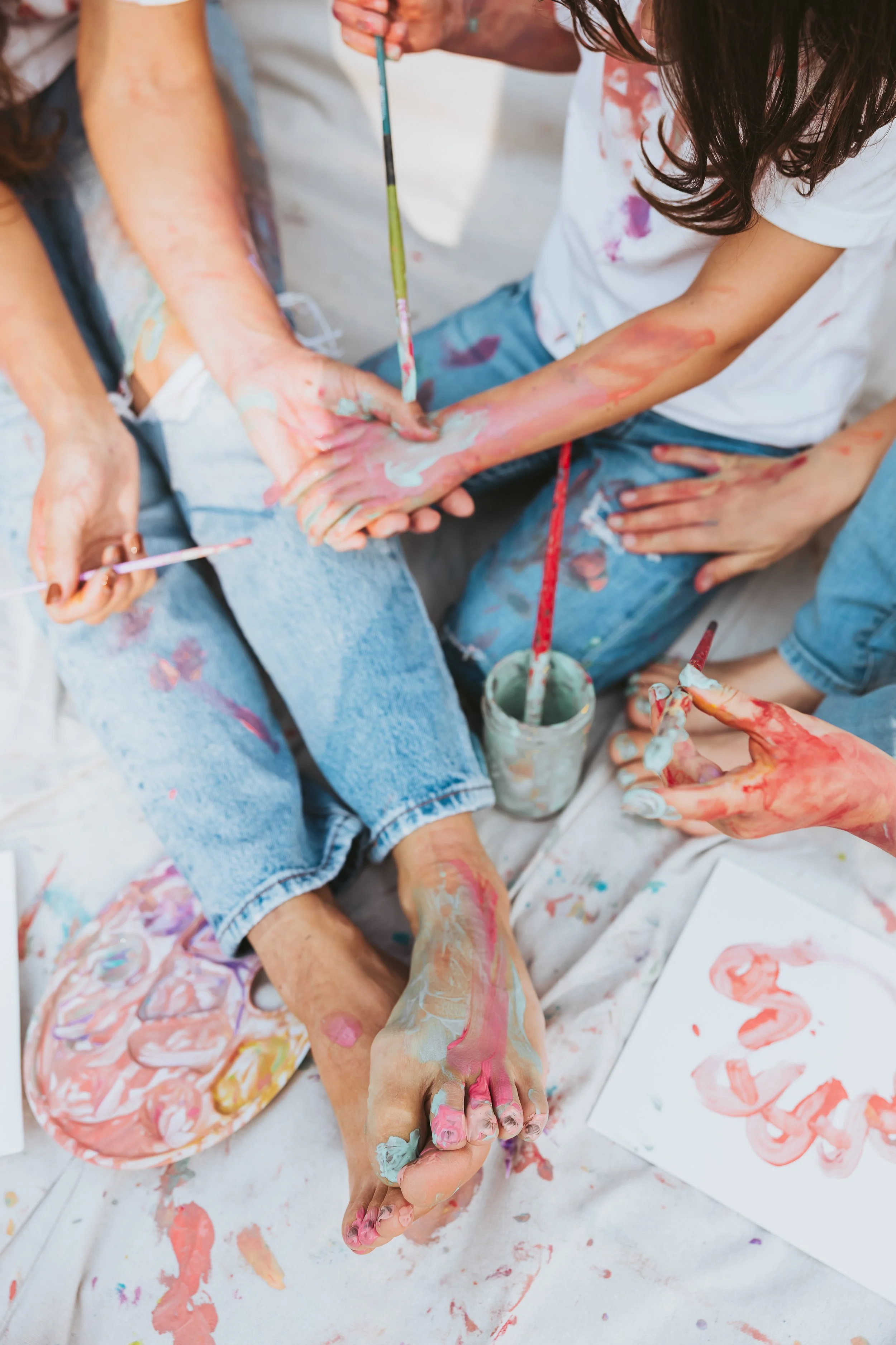 Close-up detail of paint-covered feet and paintbrushes during an artistic Alberta family paint mini photography session.