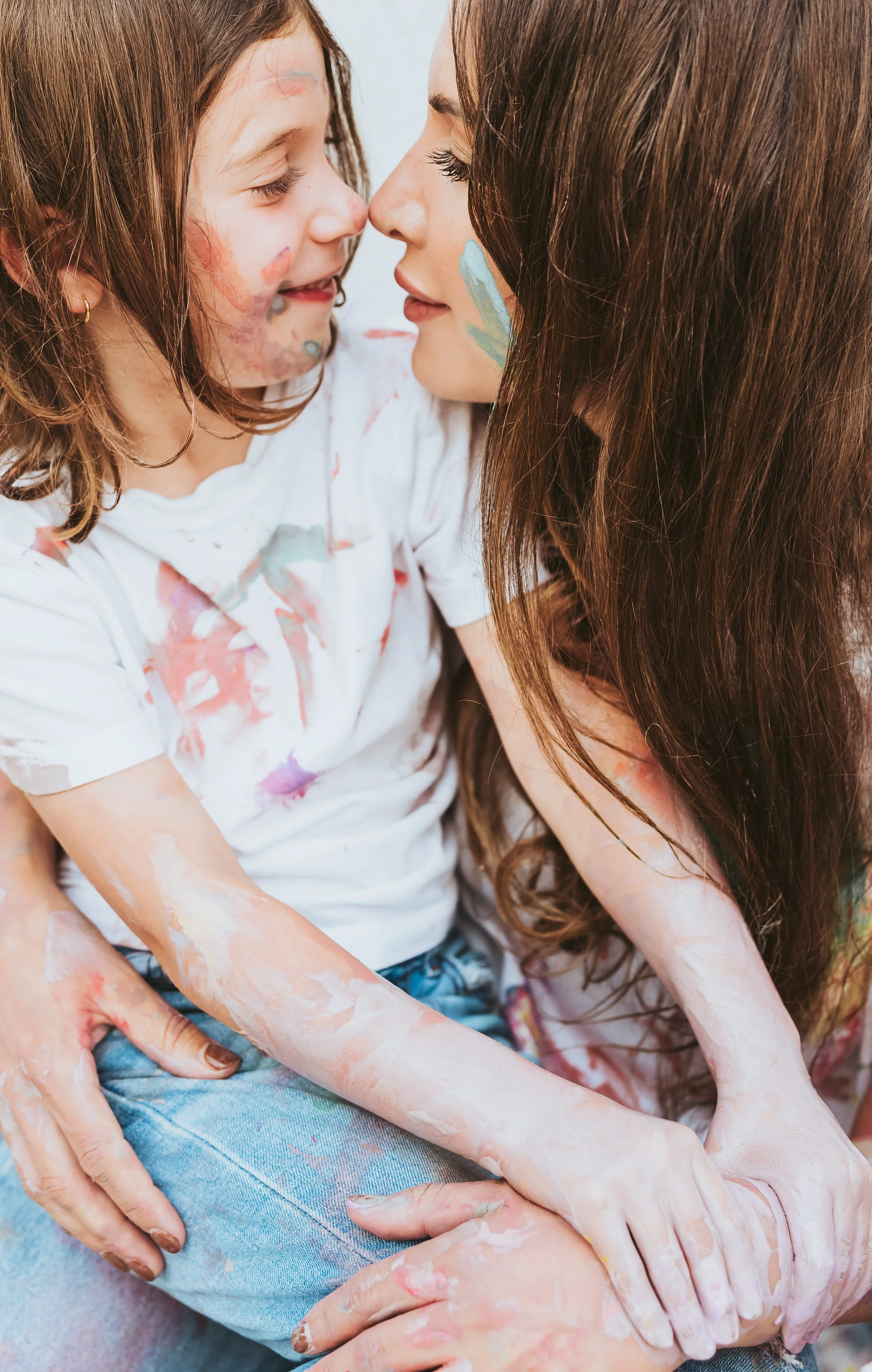 Mother hugging daughter during a storytelling-inspired paint mini family photography session in Alberta with playful artistic interaction.