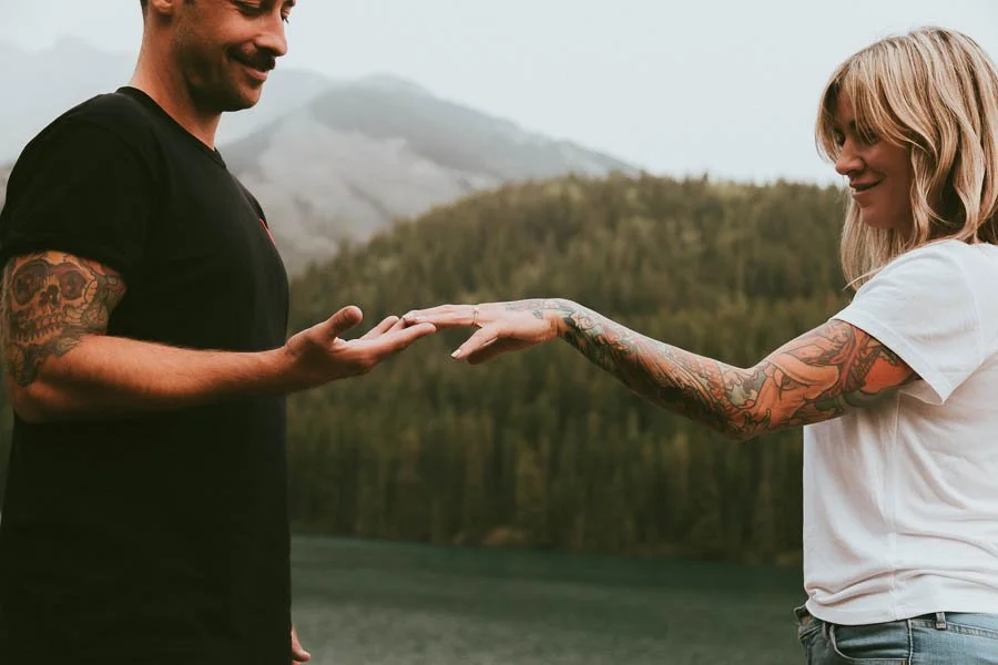 Couple during engagement session in the Rocky Mountains with golden light on alpine peaks and mountain landscape backdrop