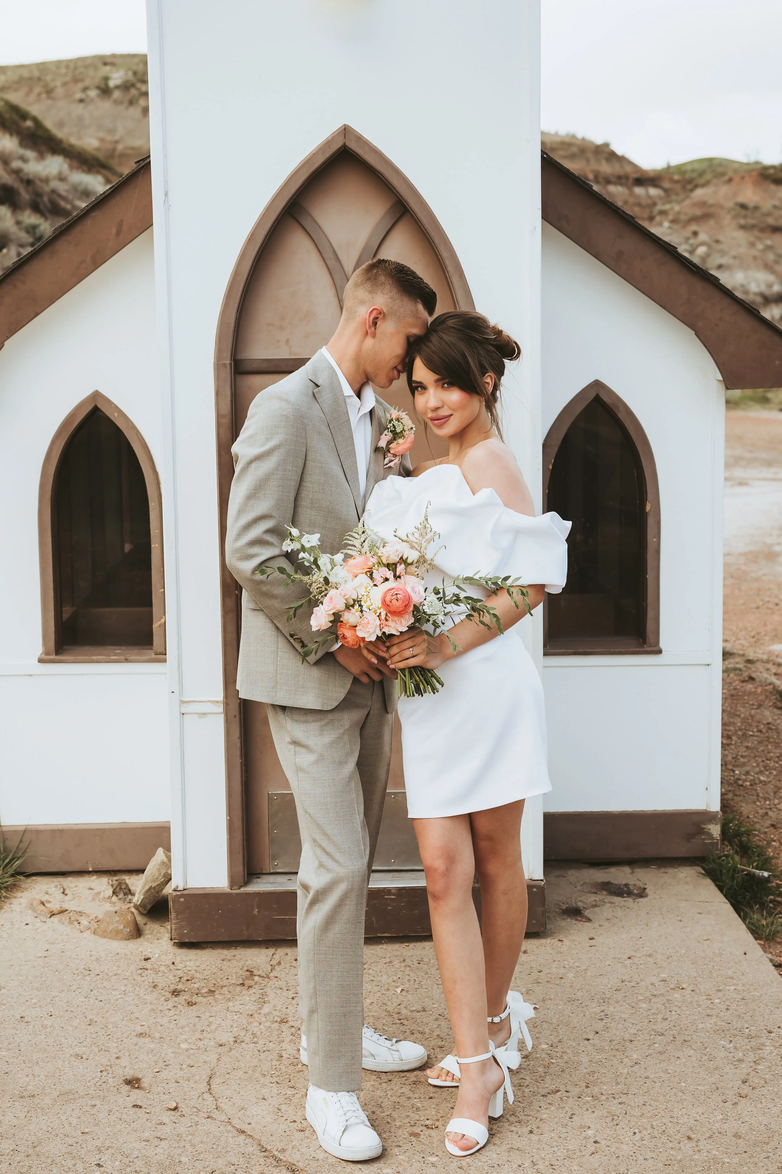 Modern bride and groom posing outside the Little Church in the Alberta Badlands during an intimate non-traditional wedding and elopement photography session.