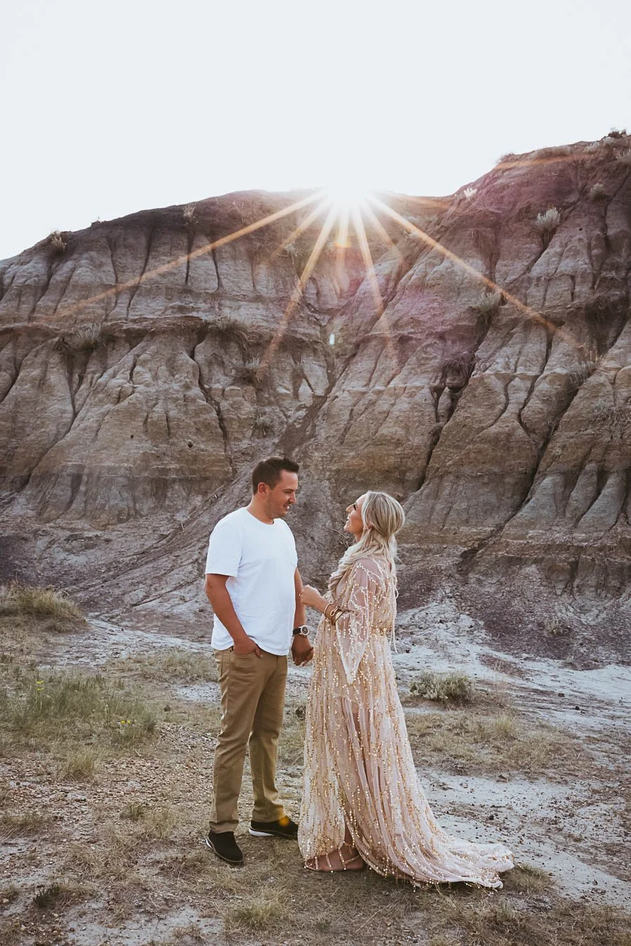 Maternity session in Horseshoe Canyon Alberta with glowing sunset light, rugged canyon textures, and romantic couple connection.