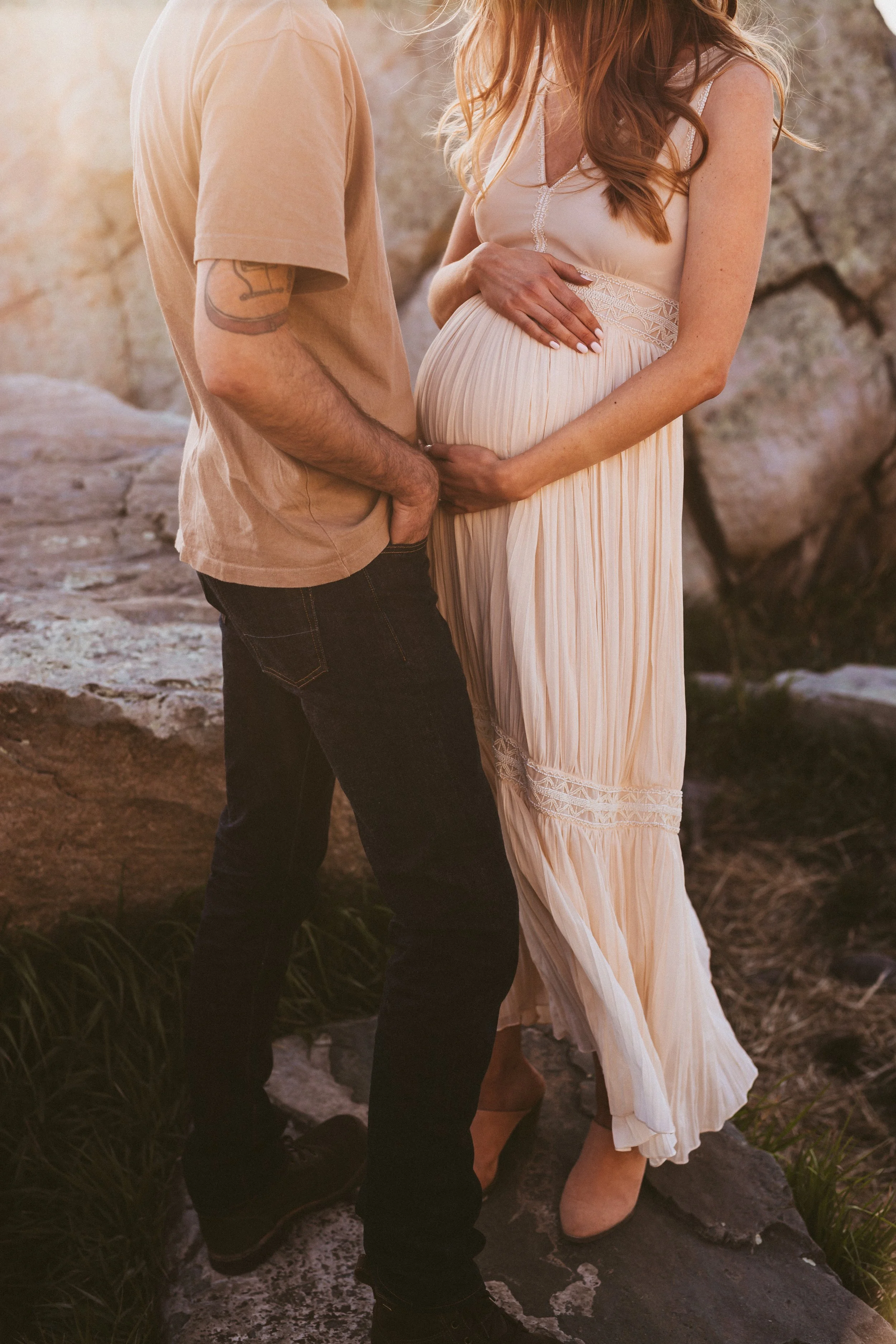 Close-up of expecting couple holding pregnant belly during a warm golden hour maternity session outdoors