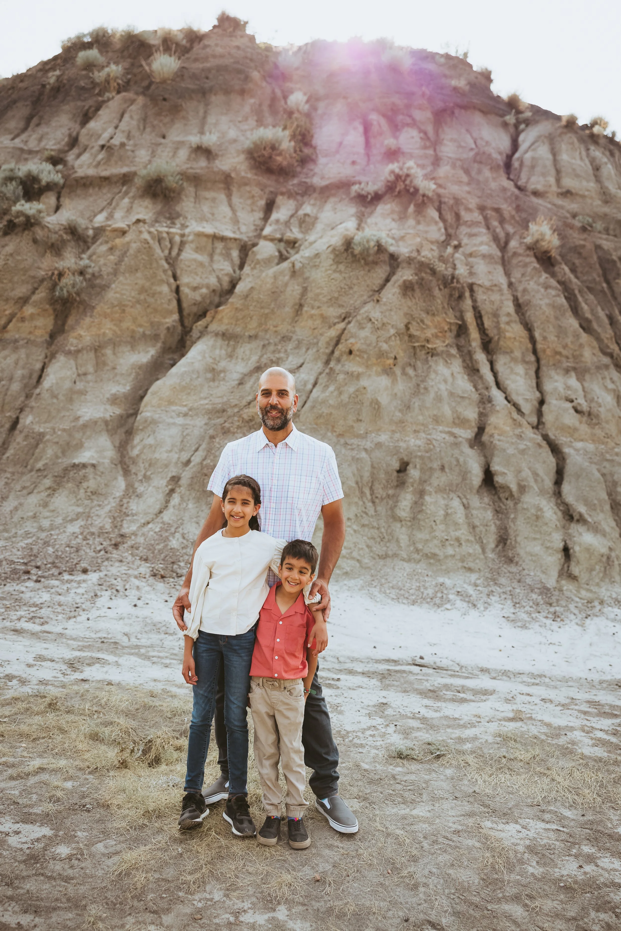 Proud father and kids standing together in the Drumheller Badlands during a natural light family photoshoot