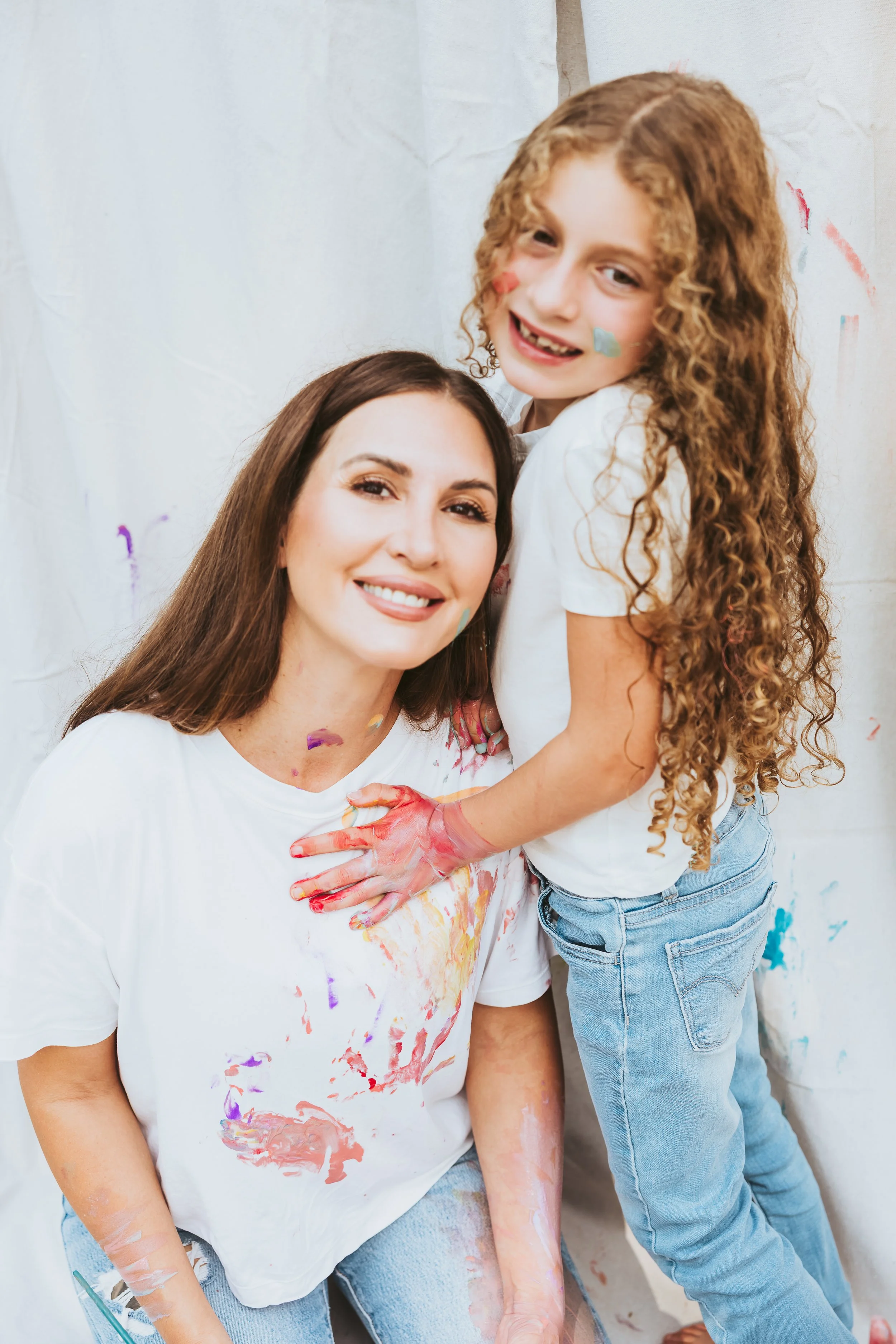 Mother and daughter snuggling during creative and messy art and paint photoshoot in Calgary Alberta.