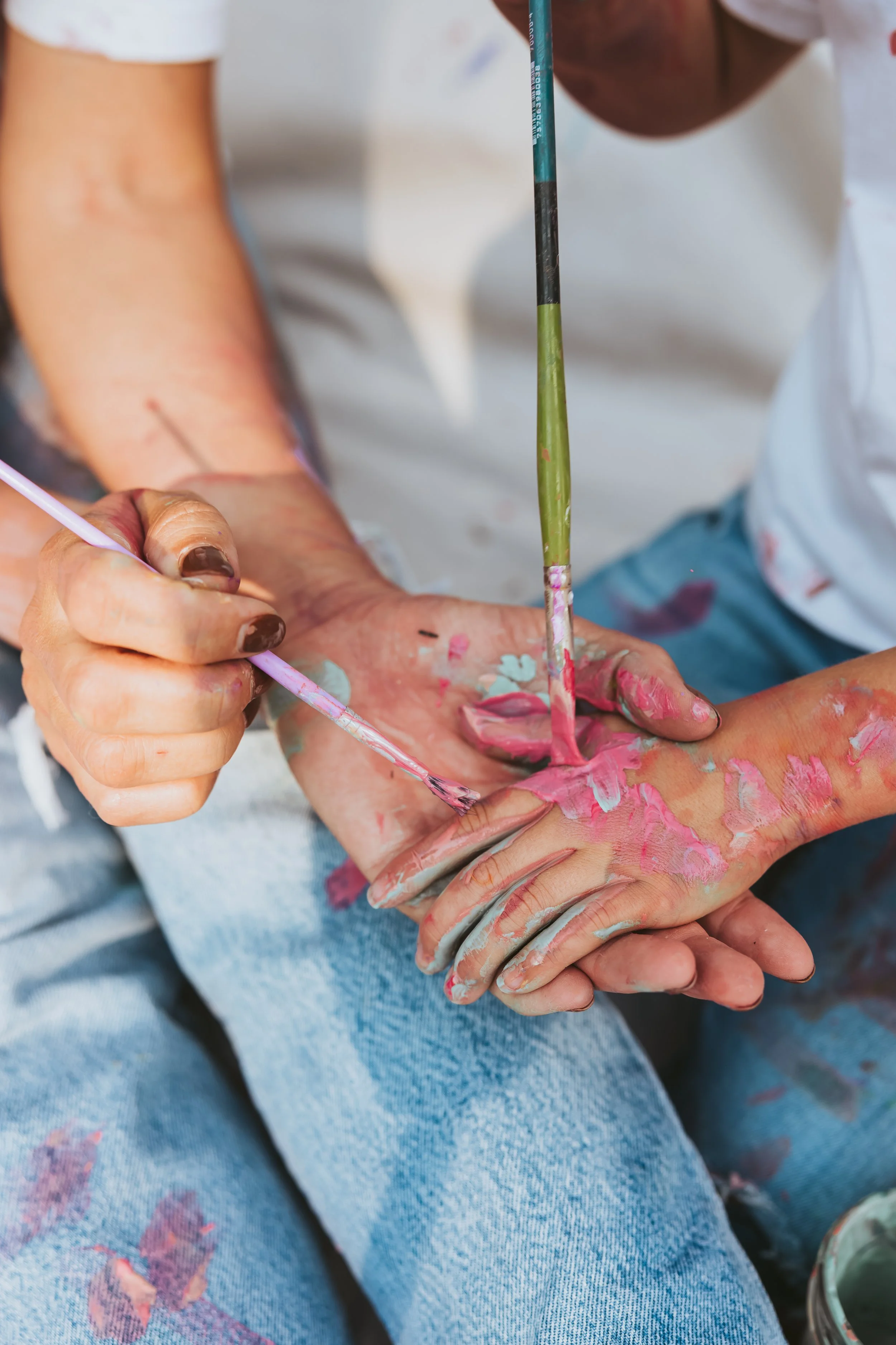 Close-up detail photo of mother and daughters with paint-covered hands during an artistic Alberta family paint mini photography session.