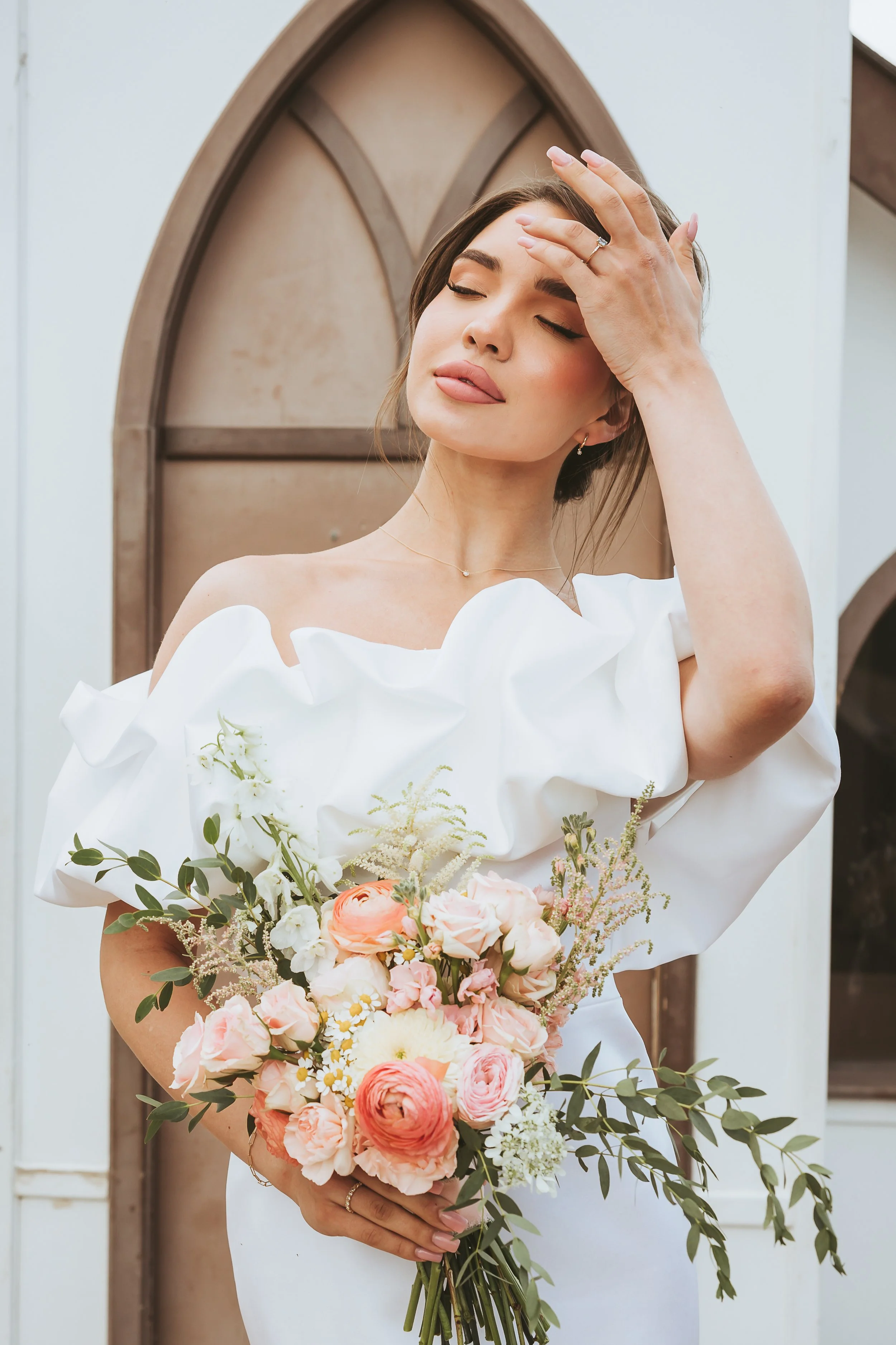 Bride in a modern short white wedding dress holding a romantic floral bouquet during an Alberta Badlands elopement photography session.