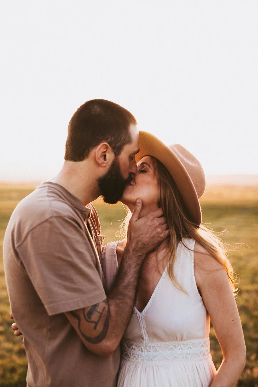 Sunset engagement session in Okotoks Alberta with couple standing in open prairie landscape and warm golden light