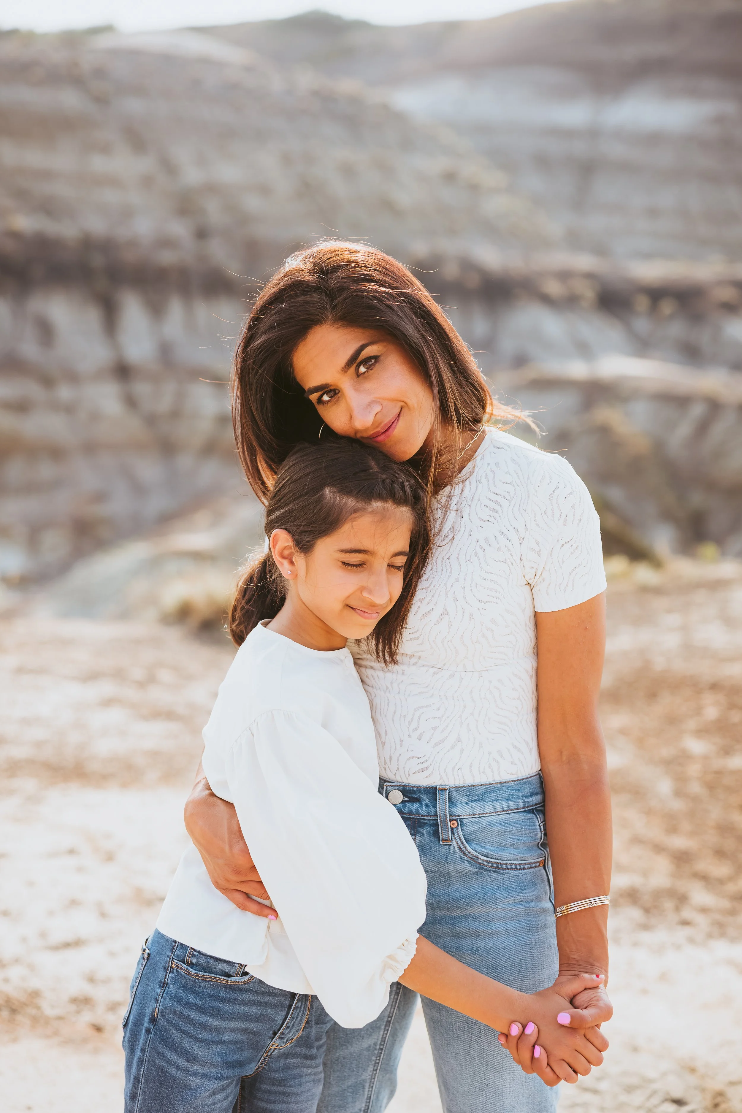 Emotional portrait of a mother and daughter embracing in the Alberta Badlands during sunset